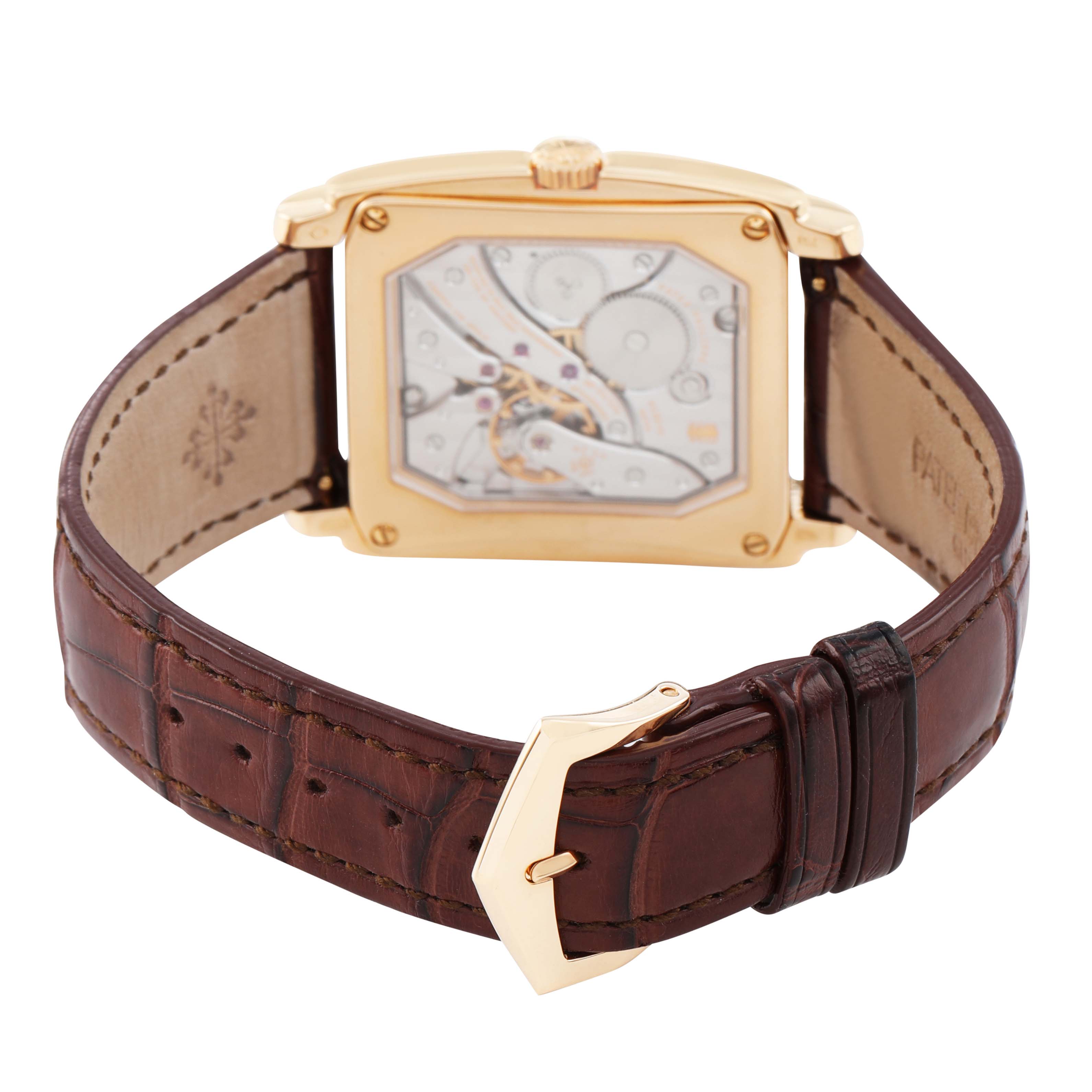 The Patek Philippe Gondolo 5124J-001 Men's Yellow Gold Silver Dial watch is shown from the back, highlighting its transparent case back and brown leather strap.