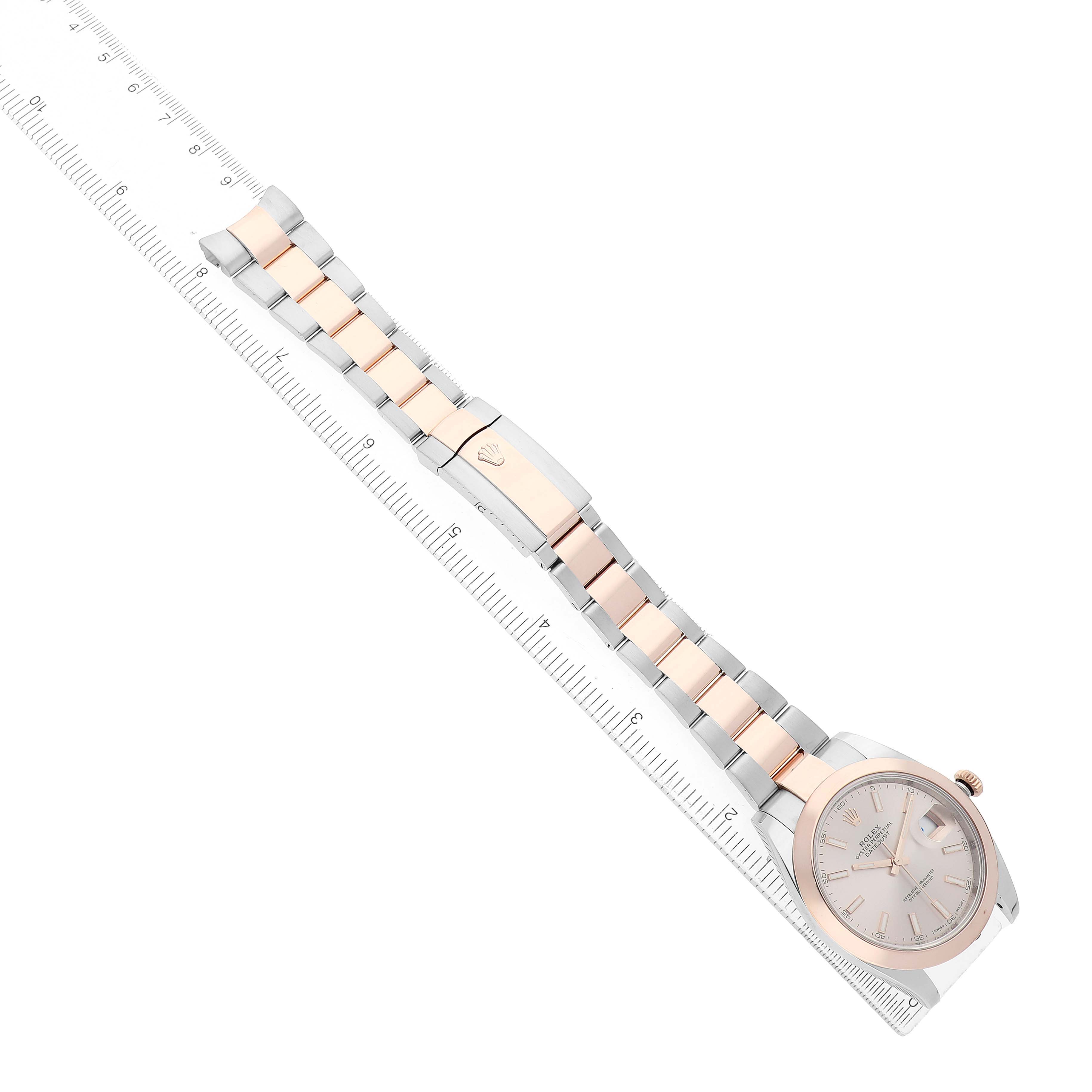 The Rolex Datejust 126301 Men's Steel and Gold (two tone) Pink Dial watch is shown at an angle displaying its dial, bracelet, and clasp alongside a ruler for scale.