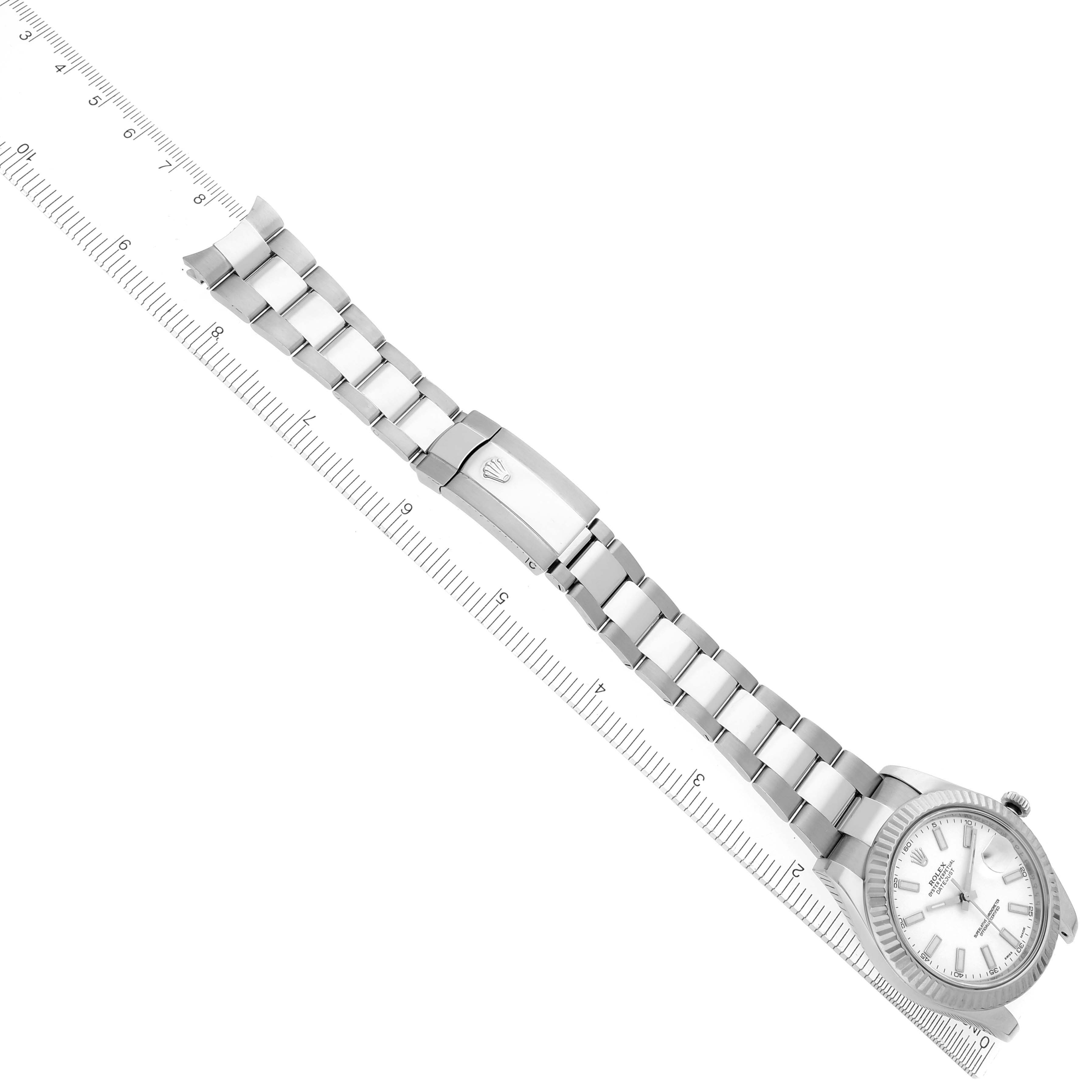 The Rolex Datejust 41 116334 Men's Stainless Steel White Dial 116334 Men's Stainless Steel White Dial is shown from a top-down angle, displaying the bracelet, clasp, and face near a ruler.