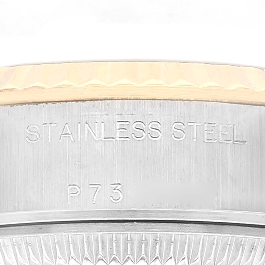 The image shows a close-up of the side of a Rolex Datejust 79173 Women's Steel and Gold (two tone) Champagne Dial 79173 Women's Steel and Gold (two tone) Champagne Dial watch case with visible stainless steel and an engraving.