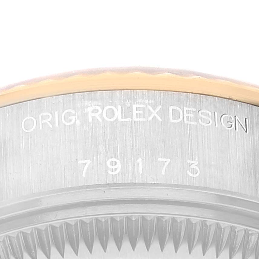This close-up image shows the case back and part of the fluted bezel of a Rolex Datejust 79173 Women's Steel and Gold (two tone) Grey Dial 79173 Women's Steel and Gold (two tone) Grey Dial watch with engraved serial numbers.