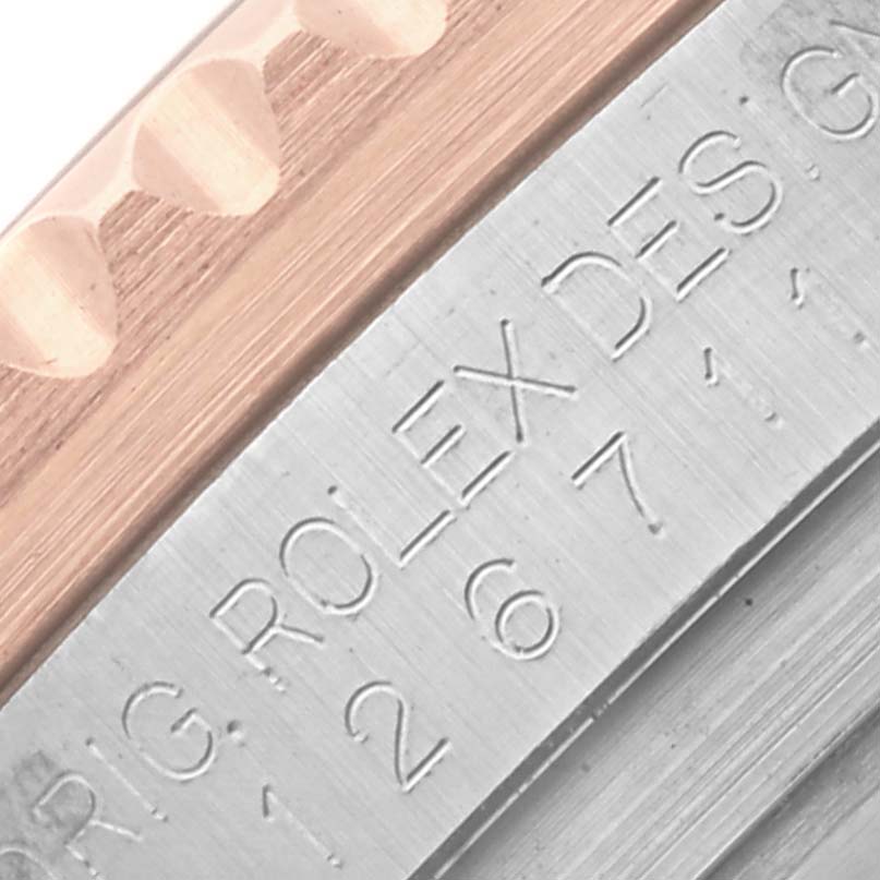 The image shows a close-up of the engraved edge and bezel of a Rolex GMT-Master 126711CHNR Men's Steel and Gold (two tone) Black Dial 126711CHNR Men's Steel and Gold (two tone) Black Dial watch.