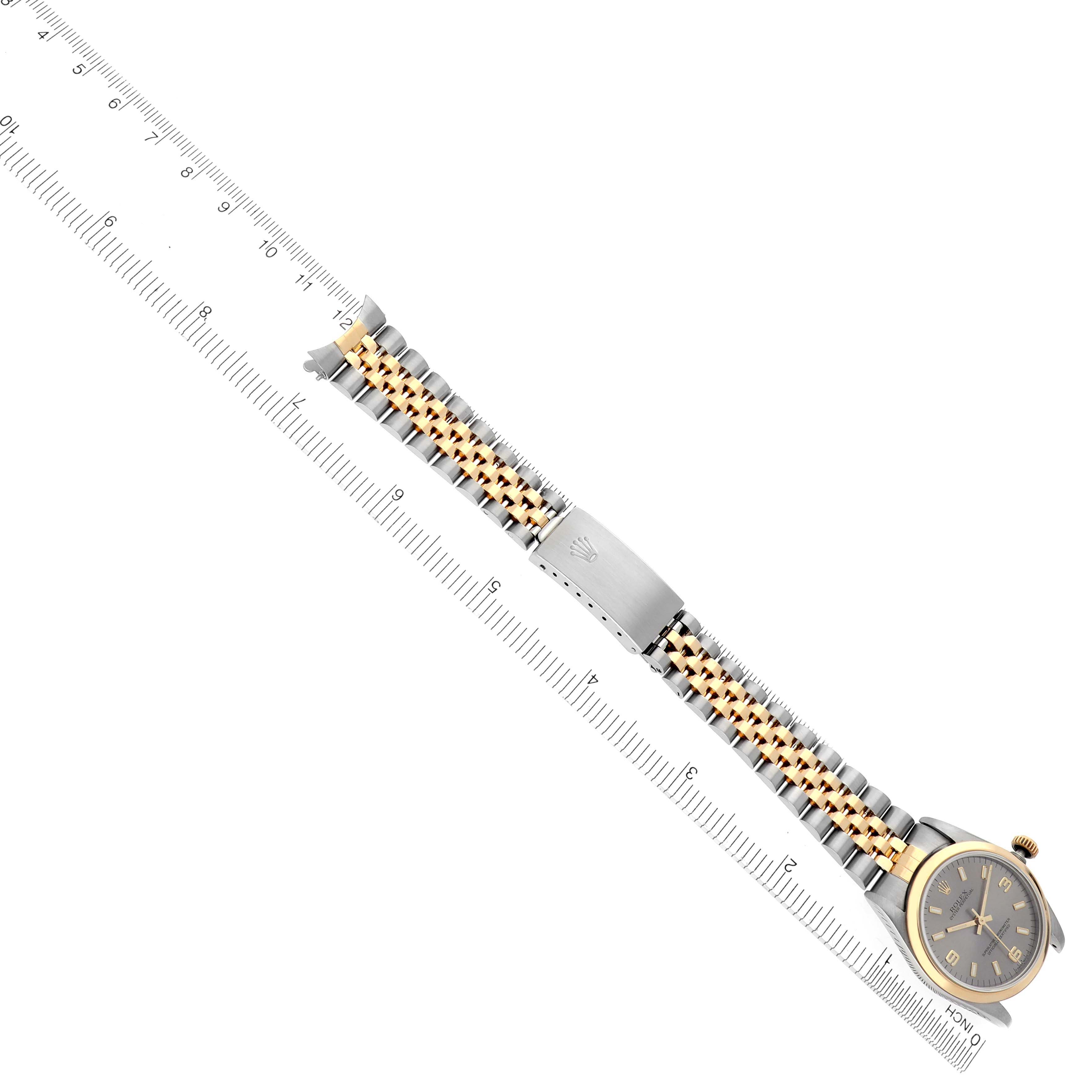 The Rolex Datejust watch is shown from a side angle, displaying the bracelet, clasp, and part of the dial with a ruler for measurement.