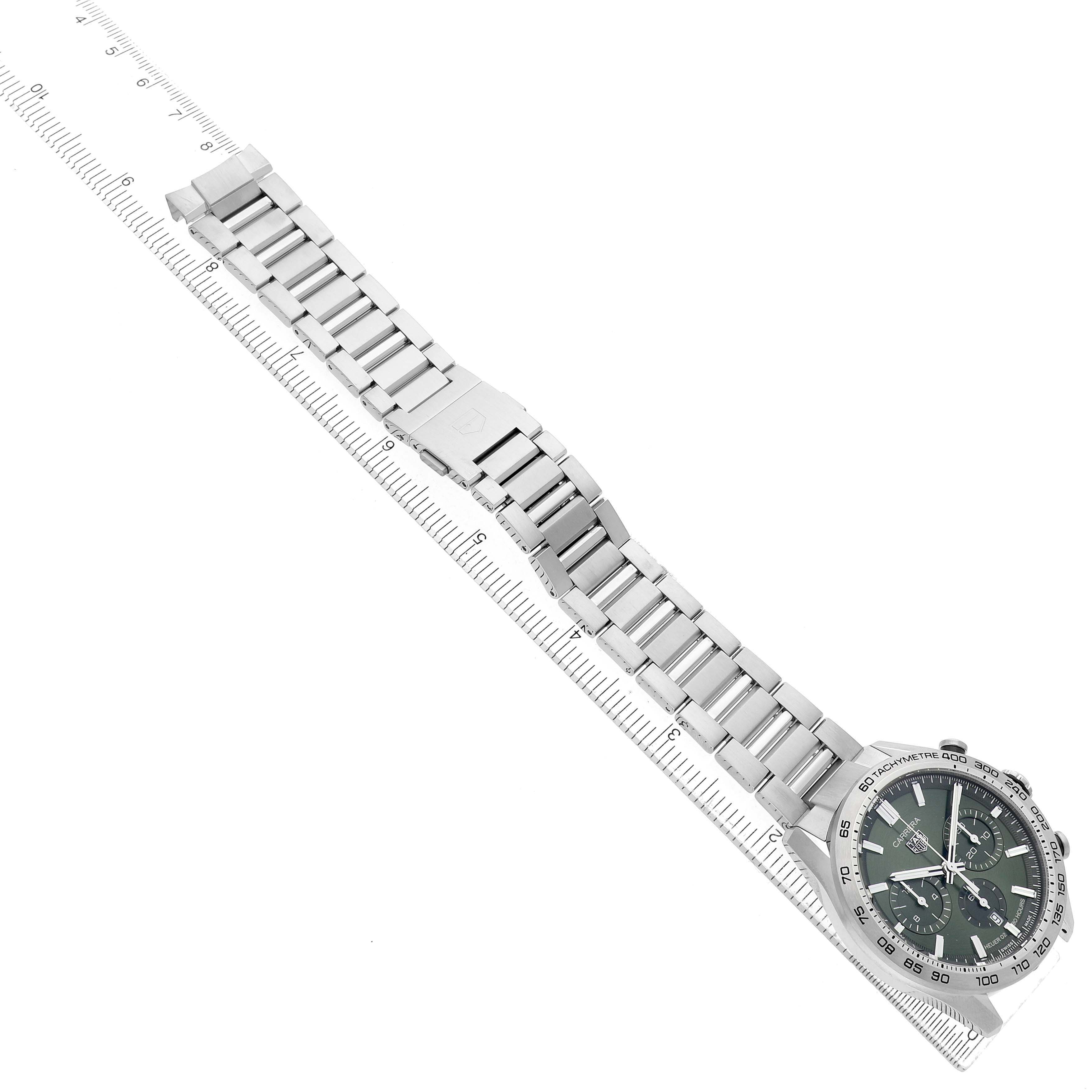 The Tag Heuer Carrera CBN2A10.BA0643 Men's Stainless Steel Green Dial watch is shown from an overhead angle, displaying its full bracelet and case on top of a ruler.