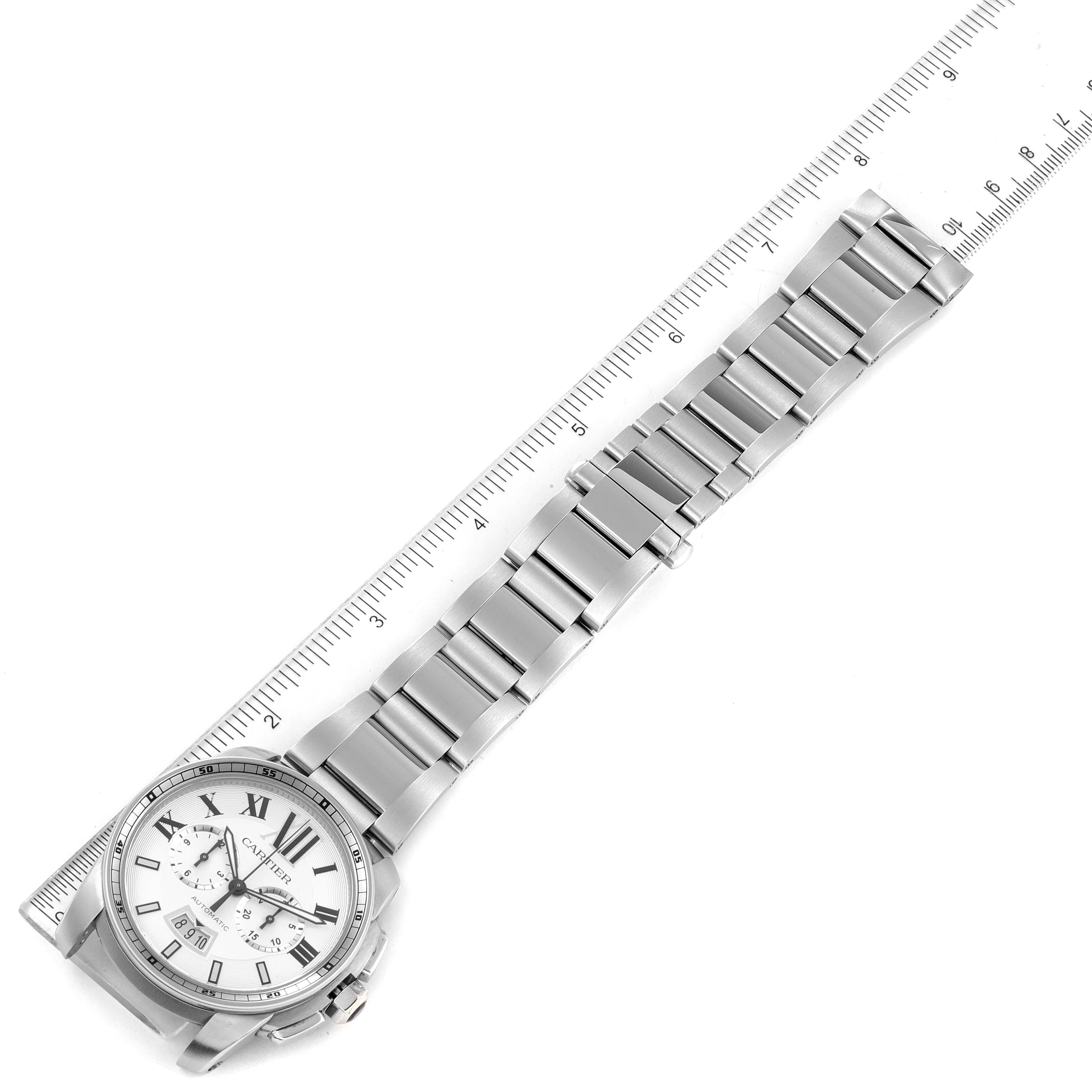 The Calibre de Cartier watch by Cartier is shown from an overhead angle, displaying the face, bracelet, and a ruler for sizing.