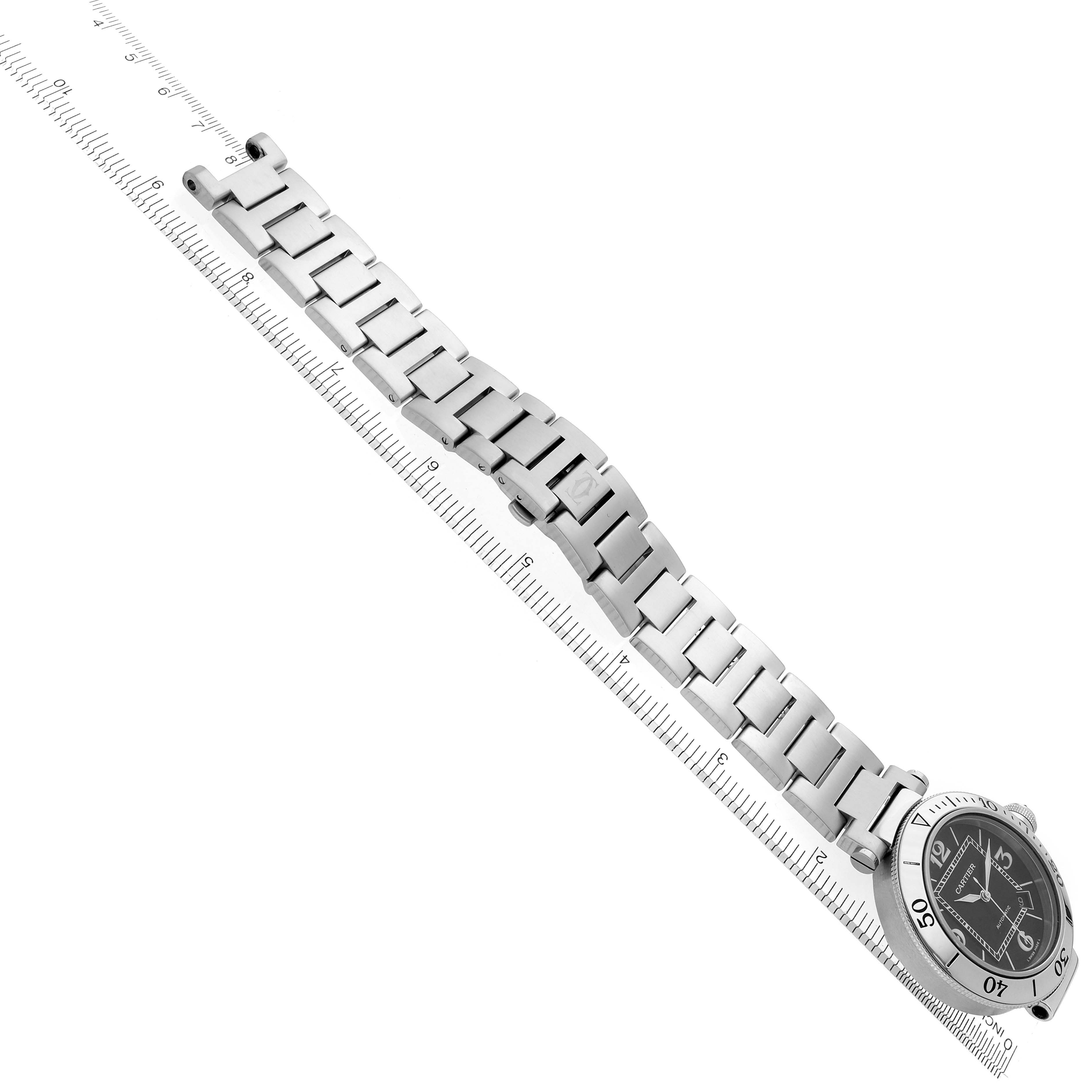 The image shows a Cartier Pasha W31077M7 Men's Stainless Steel Black Dial W31077M7 Men's Stainless Steel Black Dial watch at an angled view, highlighting the metal bracelet and face alongside a ruler for scale.