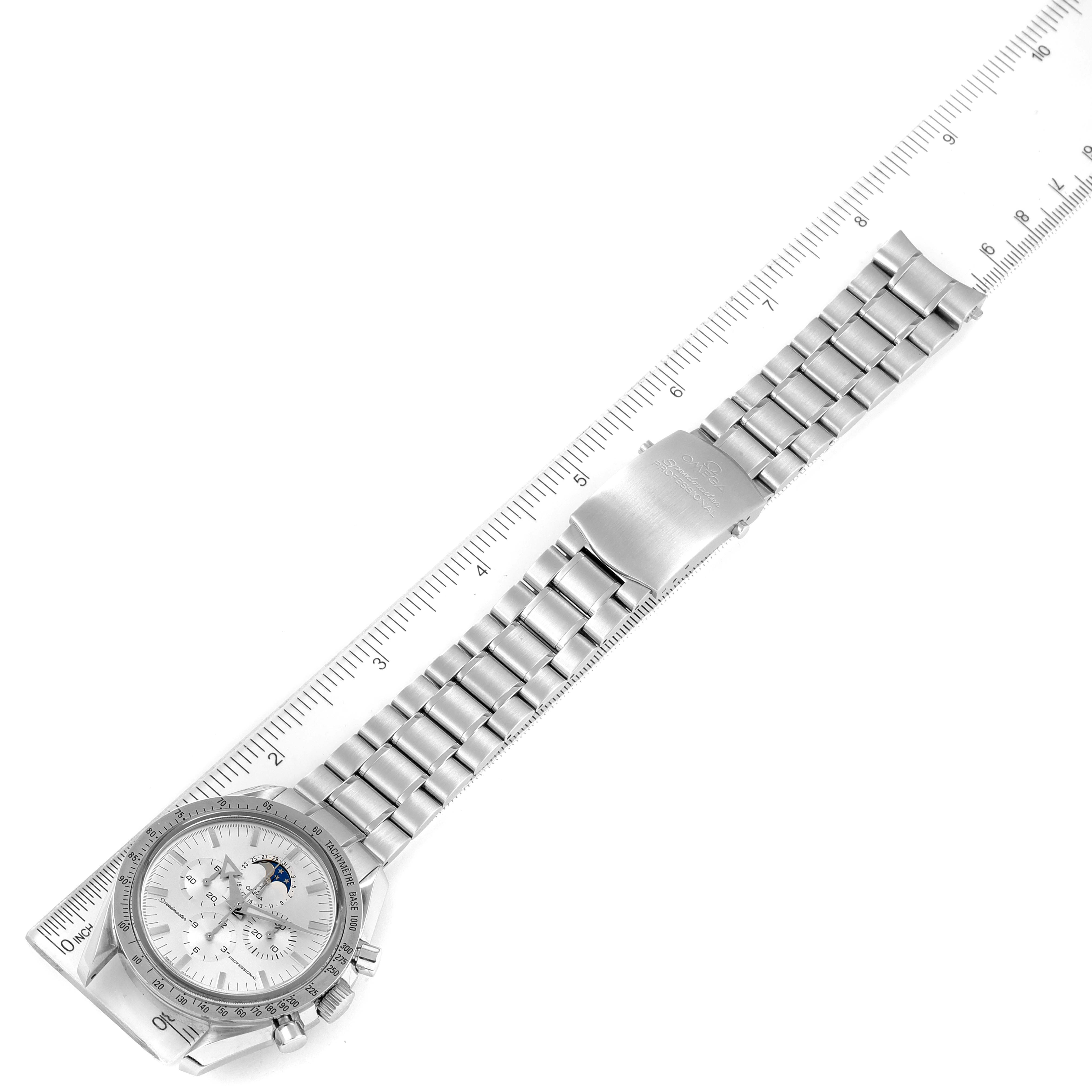 The image shows an Omega Speedmaster 3575.30.00 Men
s Stainless Steel Silver Dial 3575.30.00 Men
s Stainless Steel Silver Dial watch laid out flat diagonally next to a ruler, displaying its entire band and dial.
