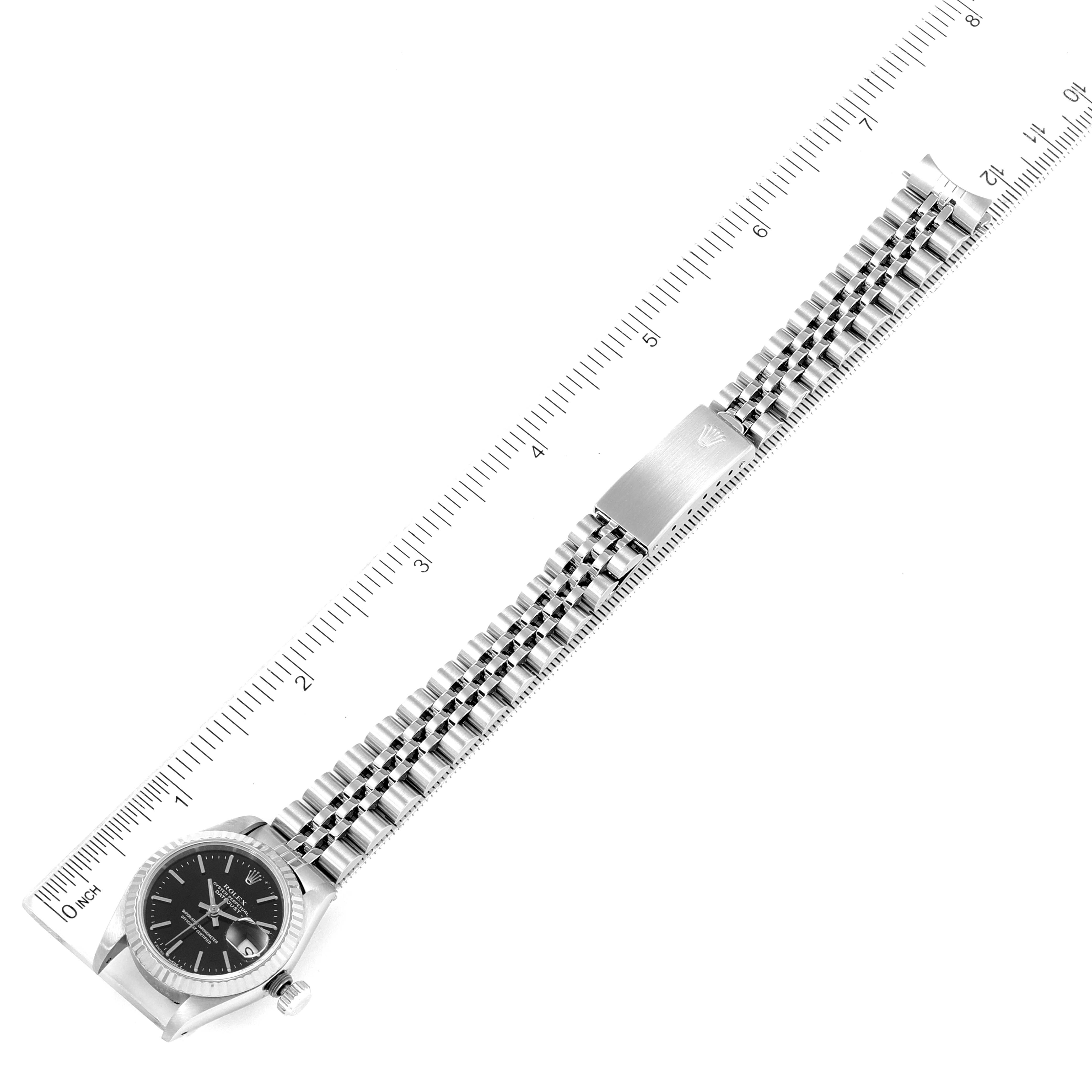 The image shows a top-down view of a Rolex Datejust 69174 Women's Stainless Steel Black Dial 69174 Women's Stainless Steel Black Dial watch with a ruler for scale.