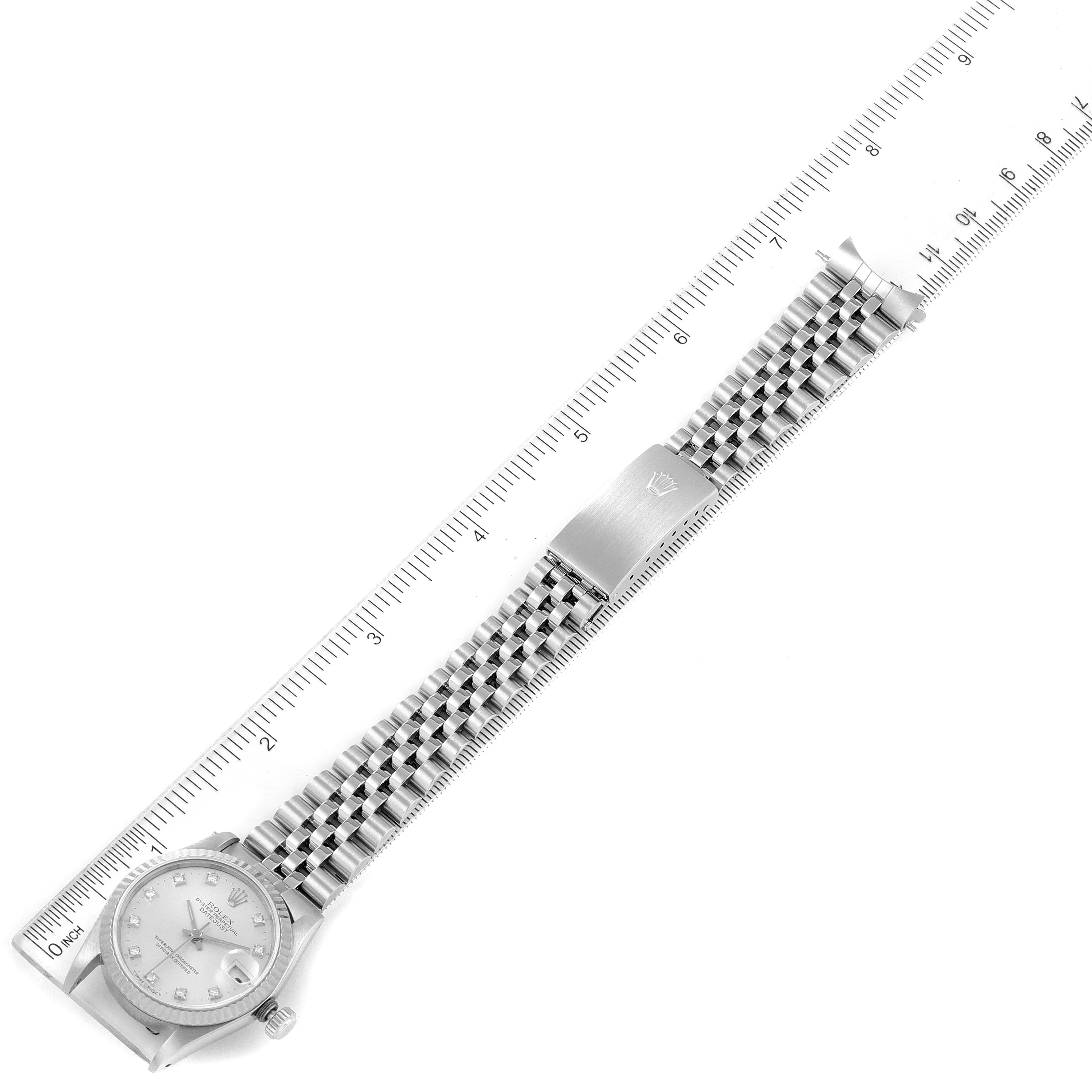 This image shows a Rolex Mid-Size 68274 Women
s Stainless Steel Silver Dial 68274 Women
s Stainless Steel Silver Dial watch from a top view, featuring the watch face, bracelet, and buckle alongside a ruler for scale.