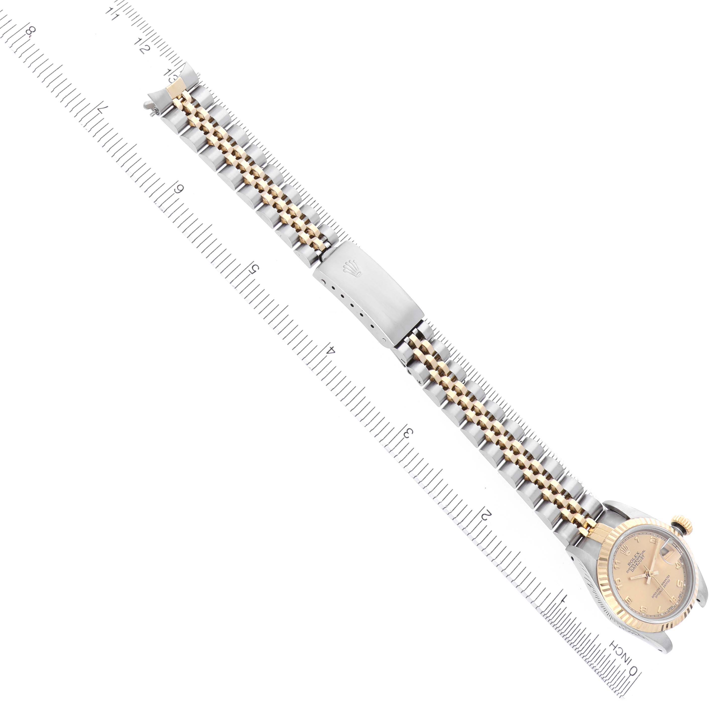 The Rolex Datejust 69173 Women's Steel and Gold (two tone) Champagne Dial 69173 Women's Steel and Gold (two tone) Champagne Dial watch is shown from an overhead angle, highlighting the full bracelet and clasp alongside a ruler for scale.