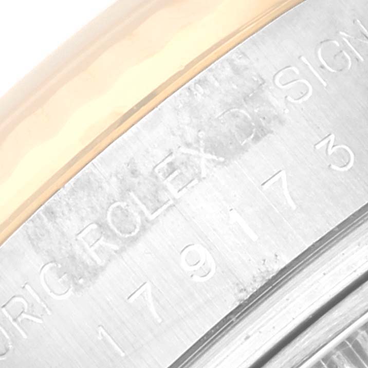 The image shows a close-up of the engraved case side of a Rolex Datejust 179173 Women's Steel and Gold (two tone) Mother of Pearl Dial 179173 Women's Steel and Gold (two tone) Mother of Pearl Dial watch, featuring part of the serial number and Rolex branding.