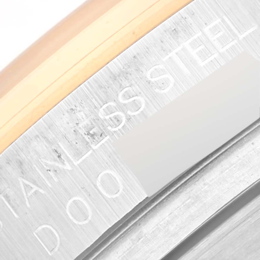 The image shows an extreme close-up of the side of a Rolex Daytona 116523 Men's Steel and Gold (two tone) Mother of Pearl Dial 116523 Men's Steel and Gold (two tone) Mother of Pearl Dial, focusing on the engraved "STAINLESS STEEL" lettering.