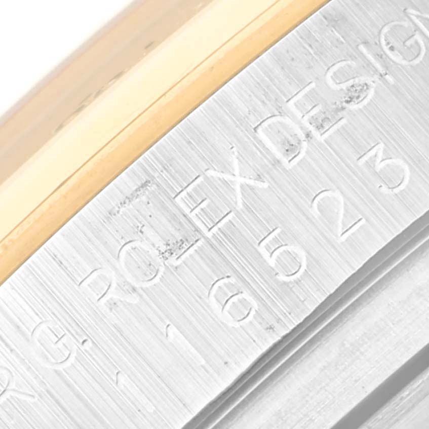 The image shows an angled, close-up view of the engraved serial number on a Rolex Daytona 116523 Men's Steel and Gold (two tone) Mother of Pearl Dial 116523 Men's Steel and Gold (two tone) Mother of Pearl Dial bezel.