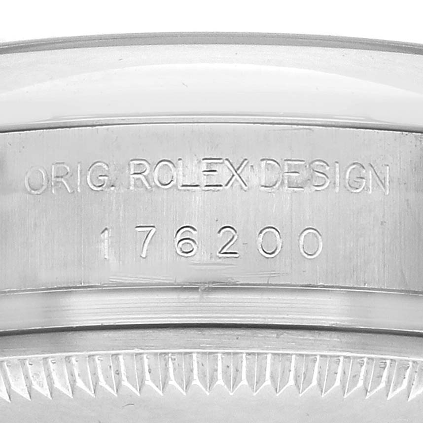 The image shows a close-up of the side of a Rolex Oyster Perpetual 176200 Women's Stainless Steel Black Dial 176200 Women's Stainless Steel Black Dial watch, highlighting the engraved serial and design numbers.