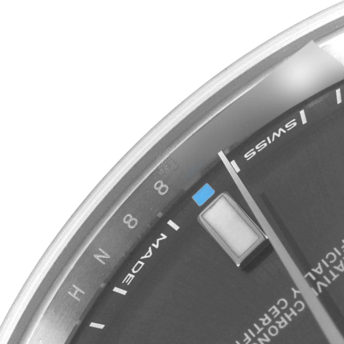 This close-up image of the Rolex Oyster Perpetual 114300 Men's Stainless Steel Grey Dial 114300 Men's Stainless Steel Grey Dial watch shows part of the dial, including hour markers and the word "SWISS."