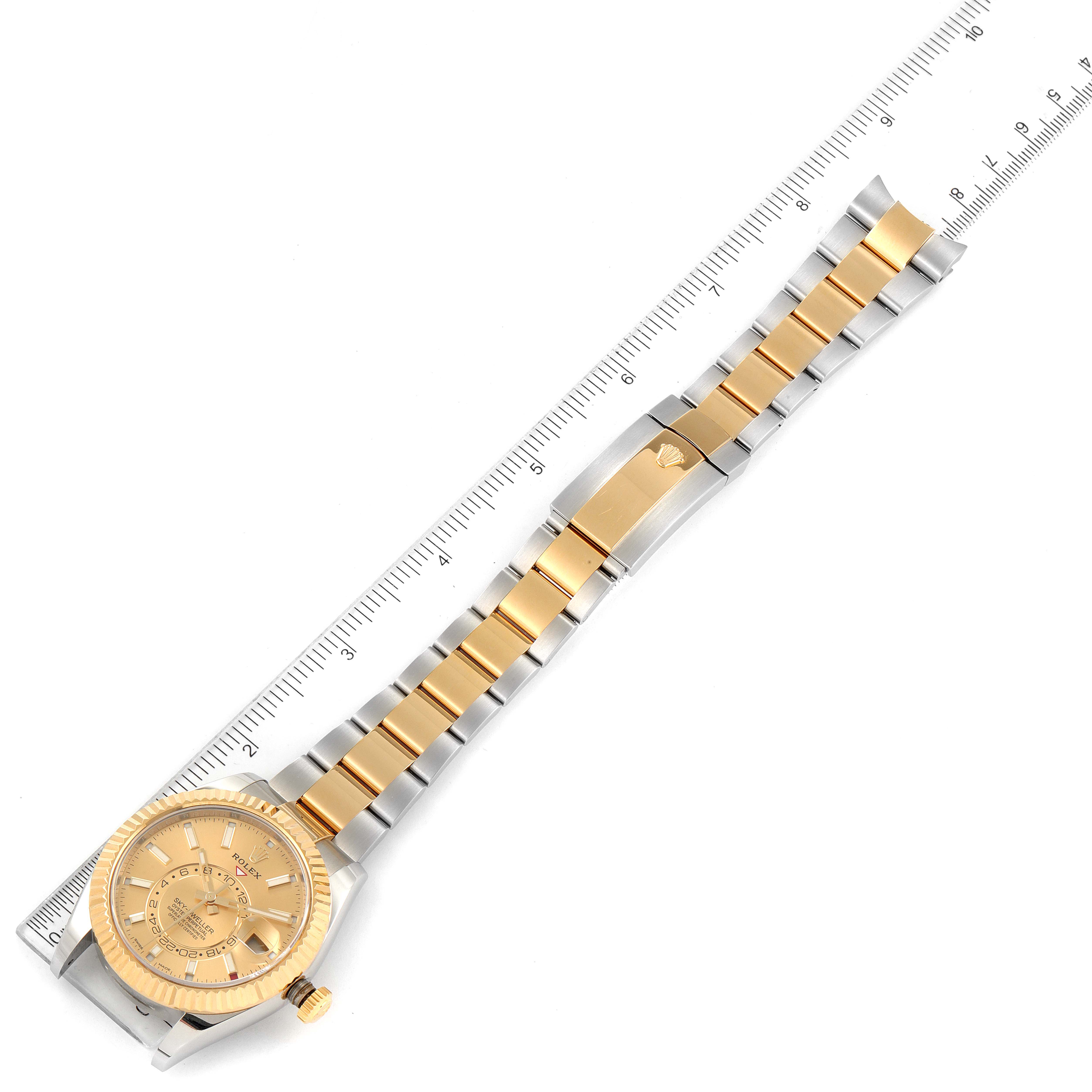 The image shows a top-down view of the entire Rolex Sky-Dweller 326933 Men's Steel and Gold (two tone) Champagne Dial 326933 Men's Steel and Gold (two tone) Champagne Dial watch, including the face, bezel, and bracelet, alongside a ruler for scale.