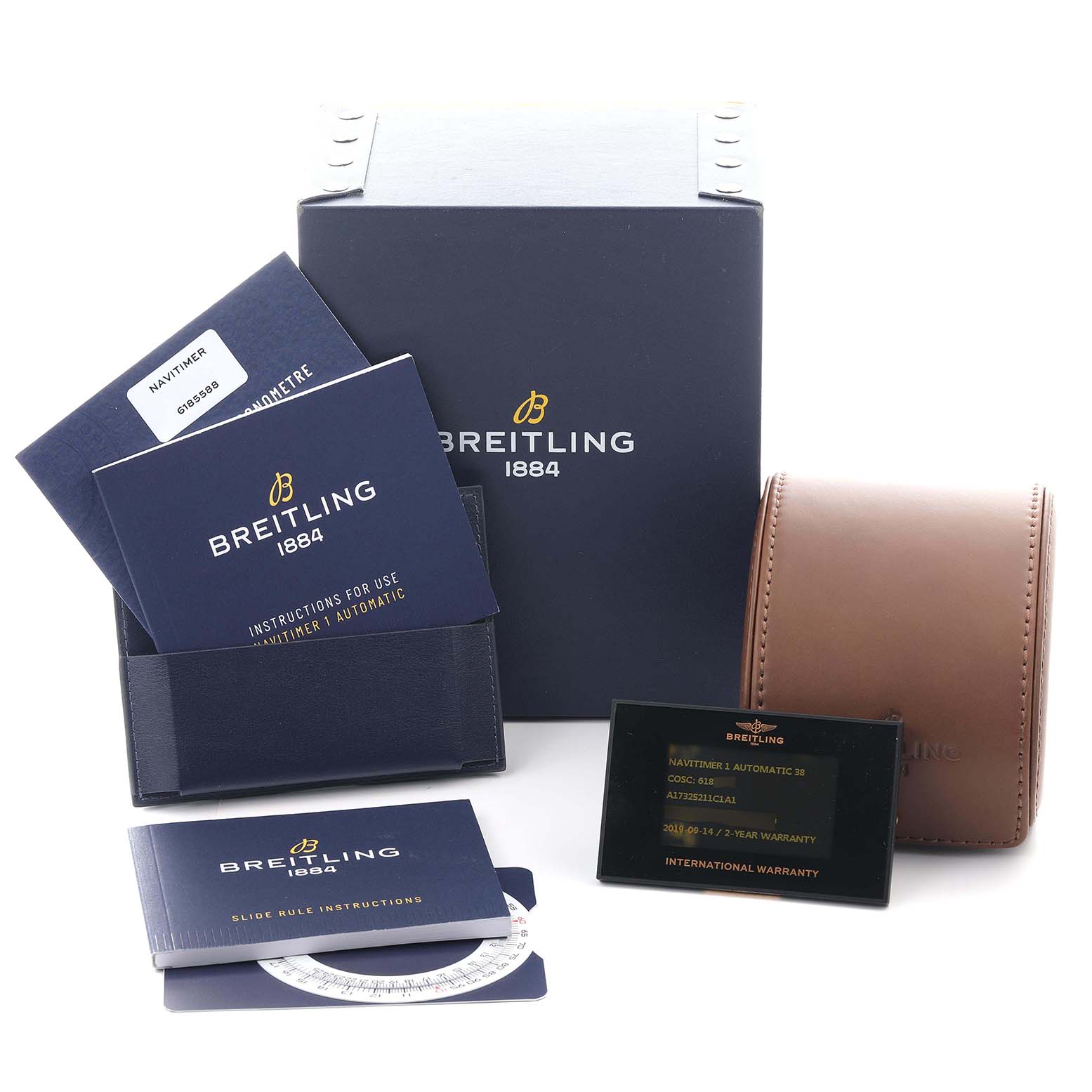 The image shows a Breitling Navitimer A17325211C1A1 Men's Stainless Steel Blue Dial A17325211C1A1 Men's Stainless Steel Blue Dial box, warranty card, manuals, and a brown watch case at a slight overhead angle.