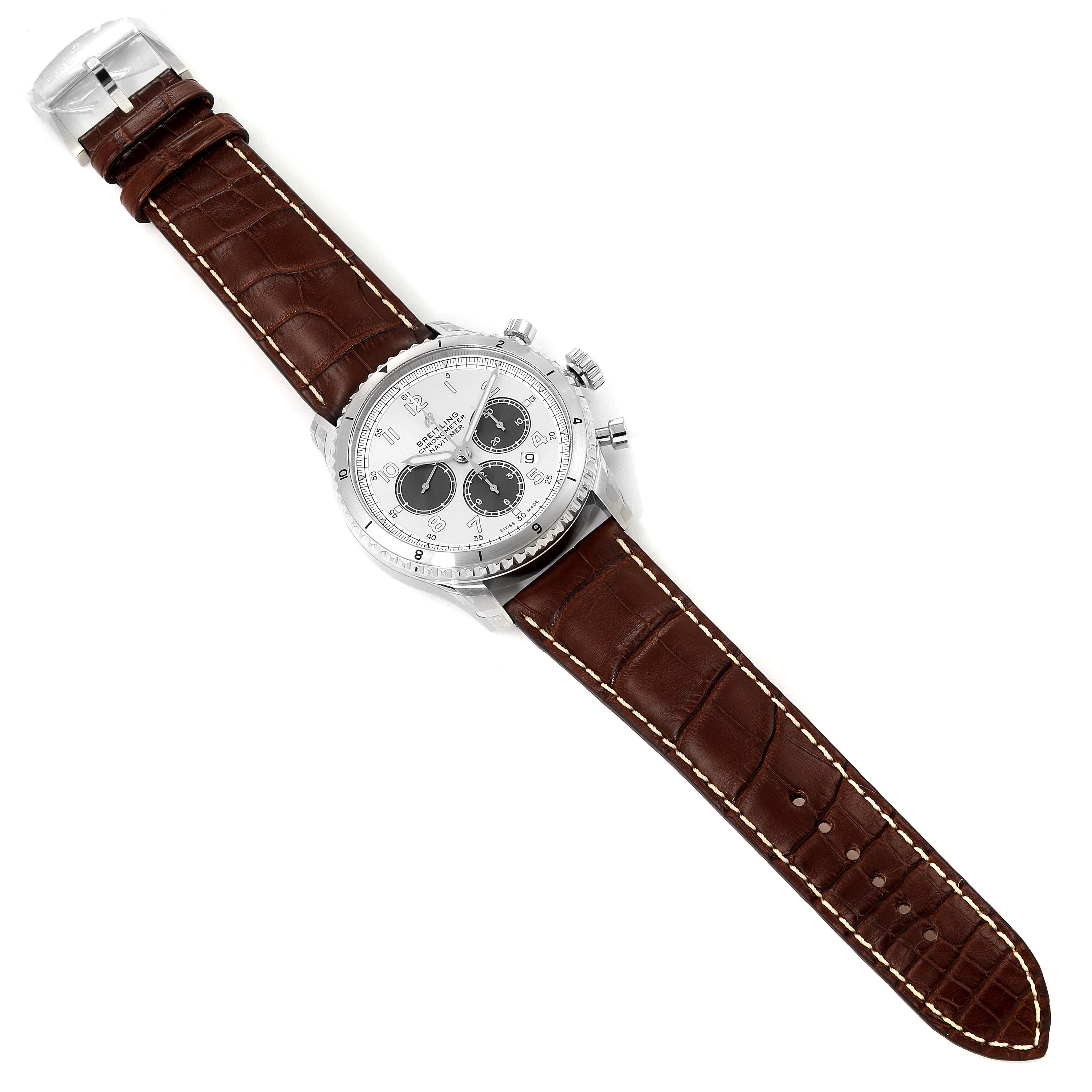 The Breitling Navitimer watch is shown from a top view, featuring a brown leather strap and a white dial with black subdials.