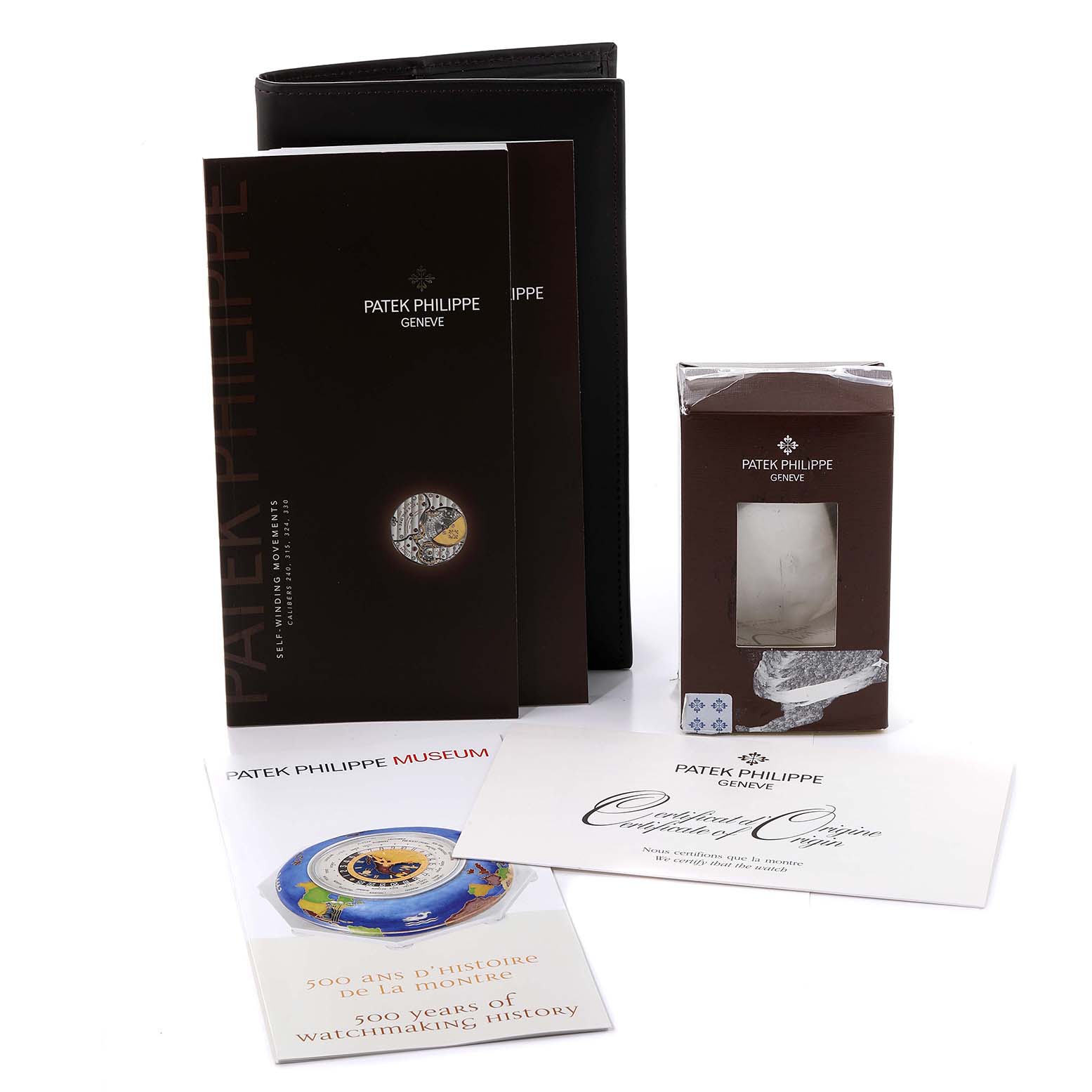 The image shows assorted accessories for the Patek Philippe Calatrava 5153J-001 Men's Yellow Gold Silver Dial 5153J-001 Men's Yellow Gold Silver Dial watch, including manuals, packaging, and certification documents.