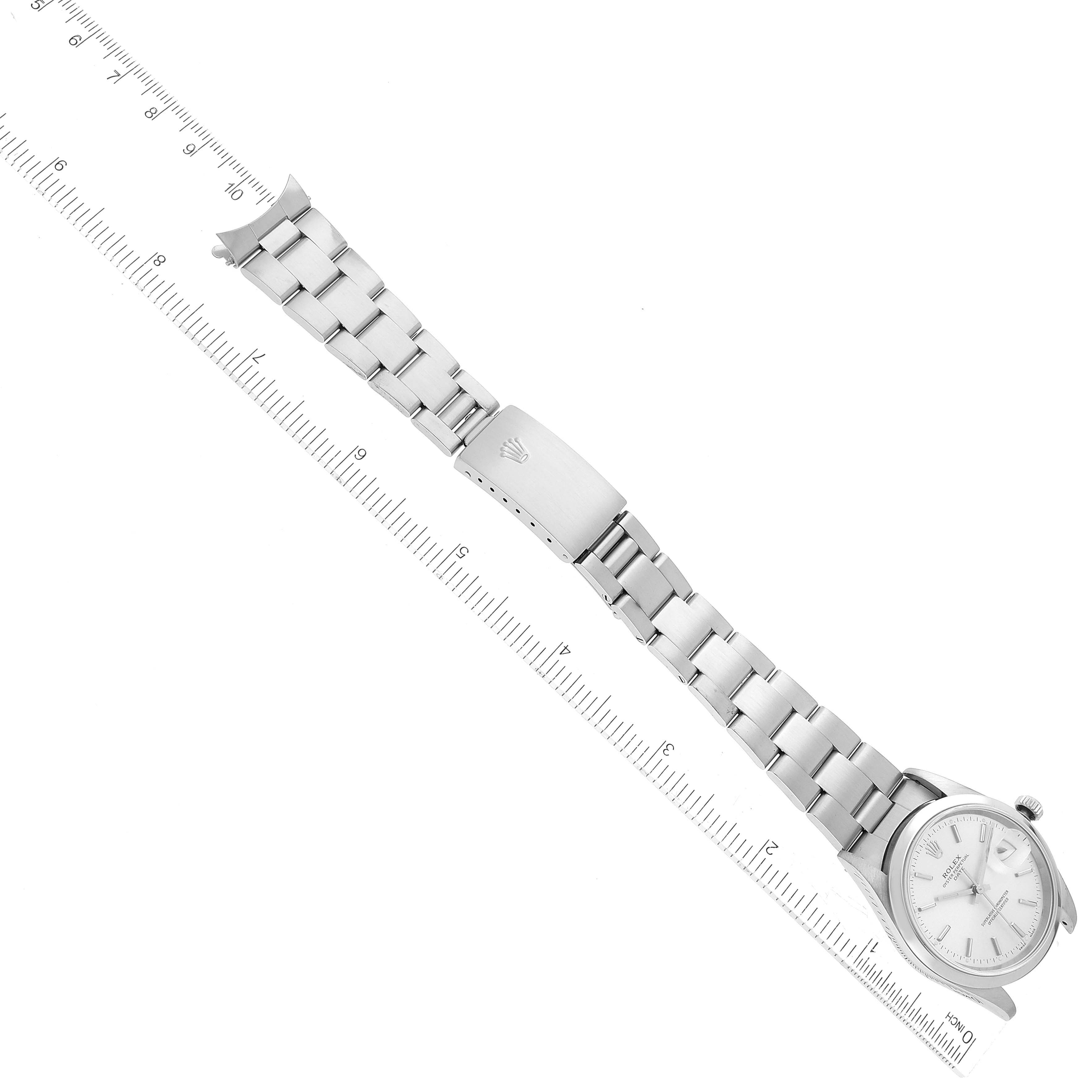 The image shows a top-down view of a Rolex Date 15200 Men's Stainless Steel Silver Dial 15200 Men's Stainless Steel Silver Dial model watch with a silver bracelet laid next to a ruler.