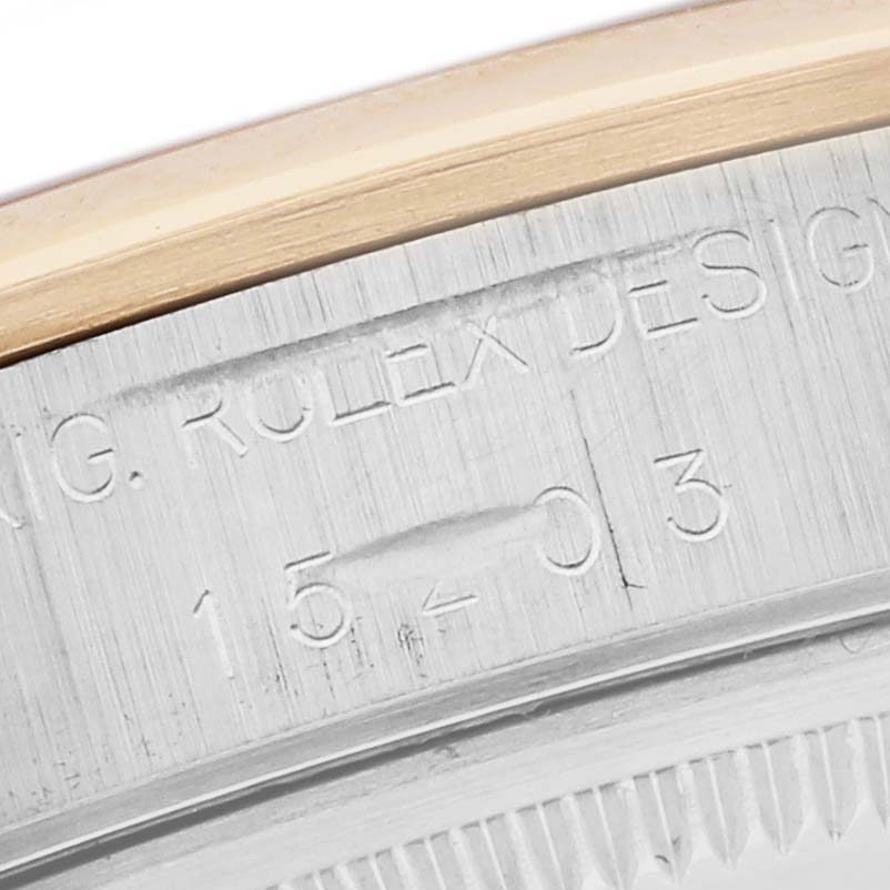 The image shows a close-up of the Rolex Date 15203 Men's Steel and Gold (two tone) Champagne Dial 15203 Men's Steel and Gold (two tone) Champagne Dial model's case with engraved text and part of the bezel.