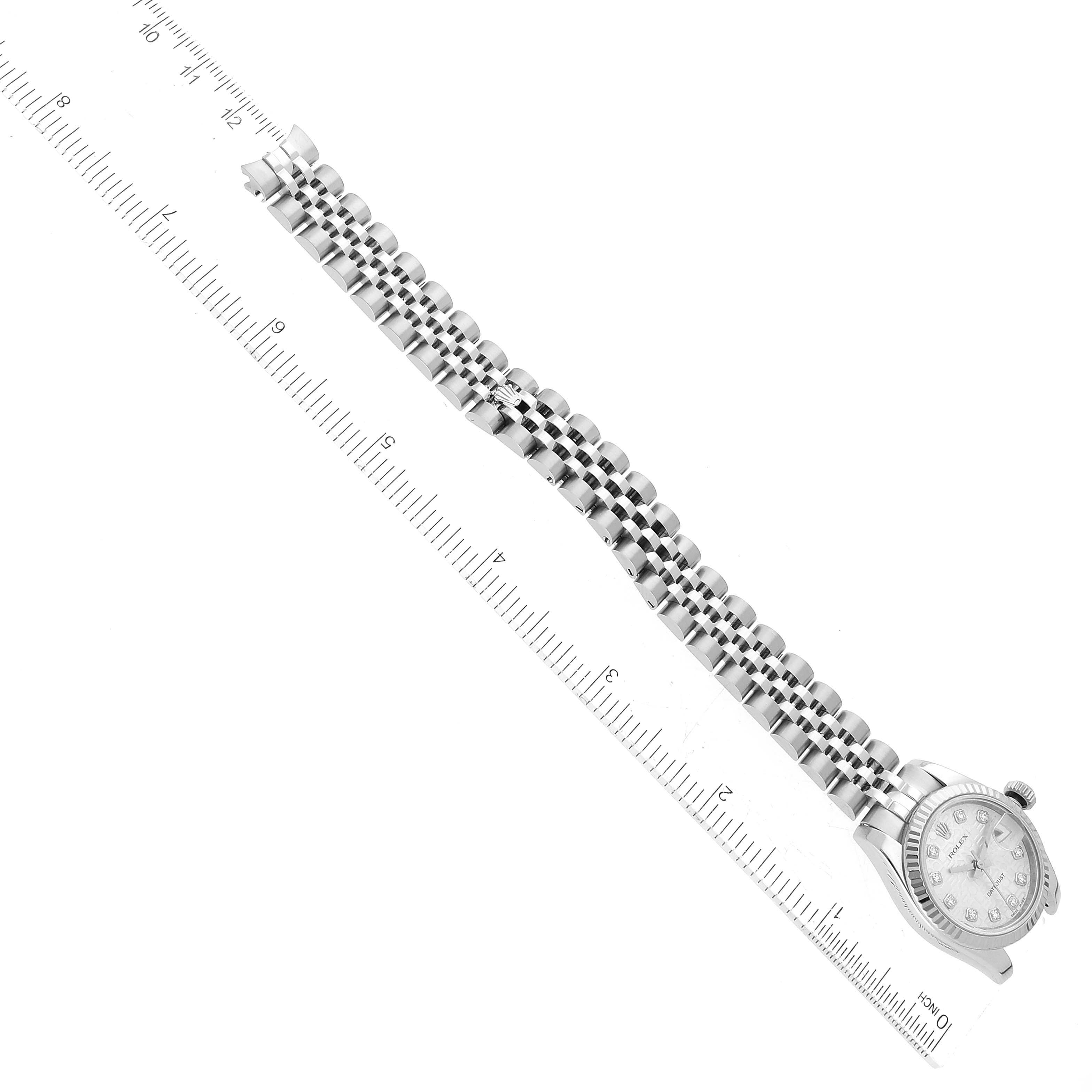 The image shows an aerial view of a Rolex Datejust 179174 Women's Stainless Steel Silver Dial 179174 Women's Stainless Steel Silver Dial watch with a ruler placed alongside its bracelet.