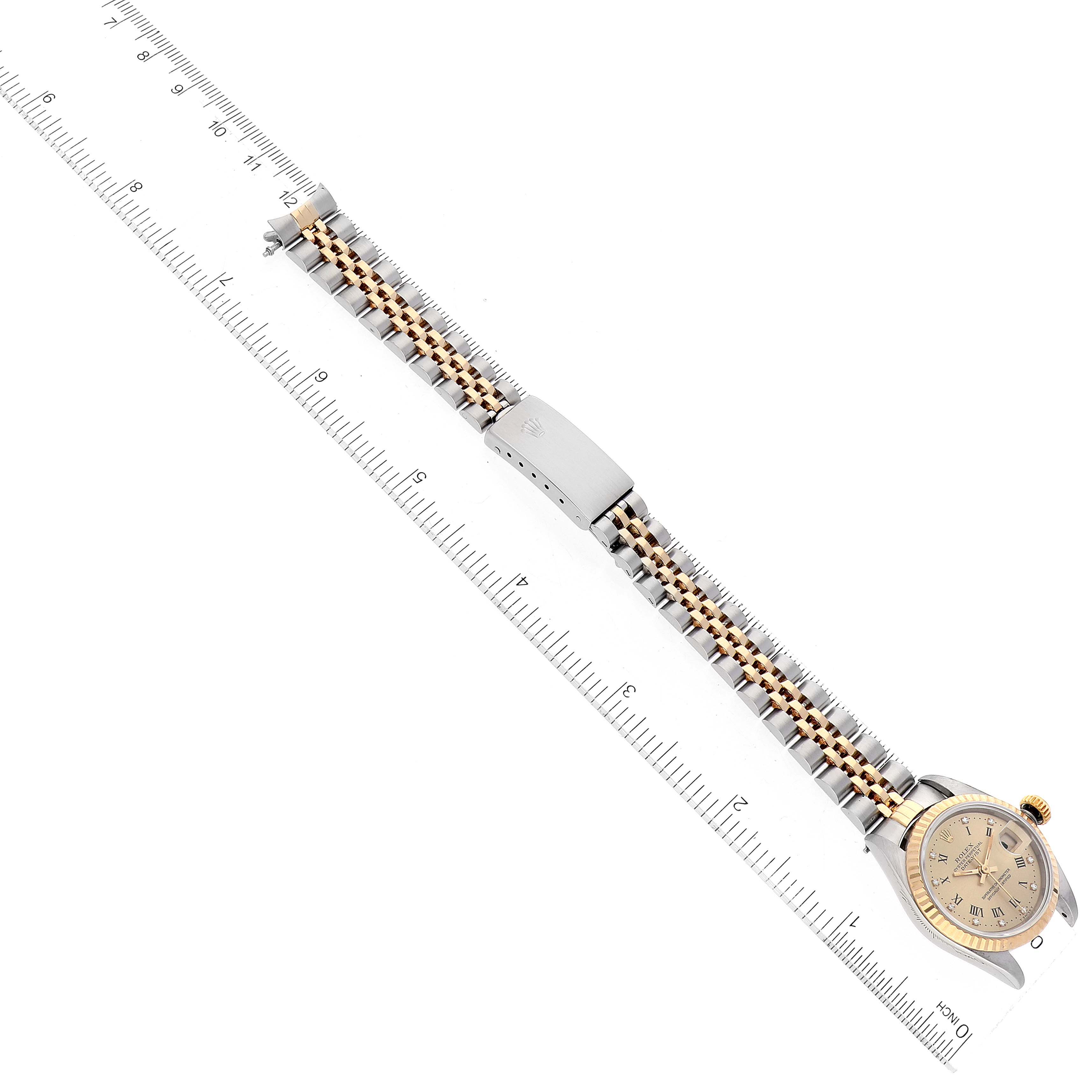 The Rolex Datejust 69173 Women's Steel and Gold (two tone) Champagne Dial 69173 Women's Steel and Gold (two tone) Champagne Dial watch is shown from a top-down angle, displaying the face, bezel, bracelet, and clasp, aligned with a ruler.