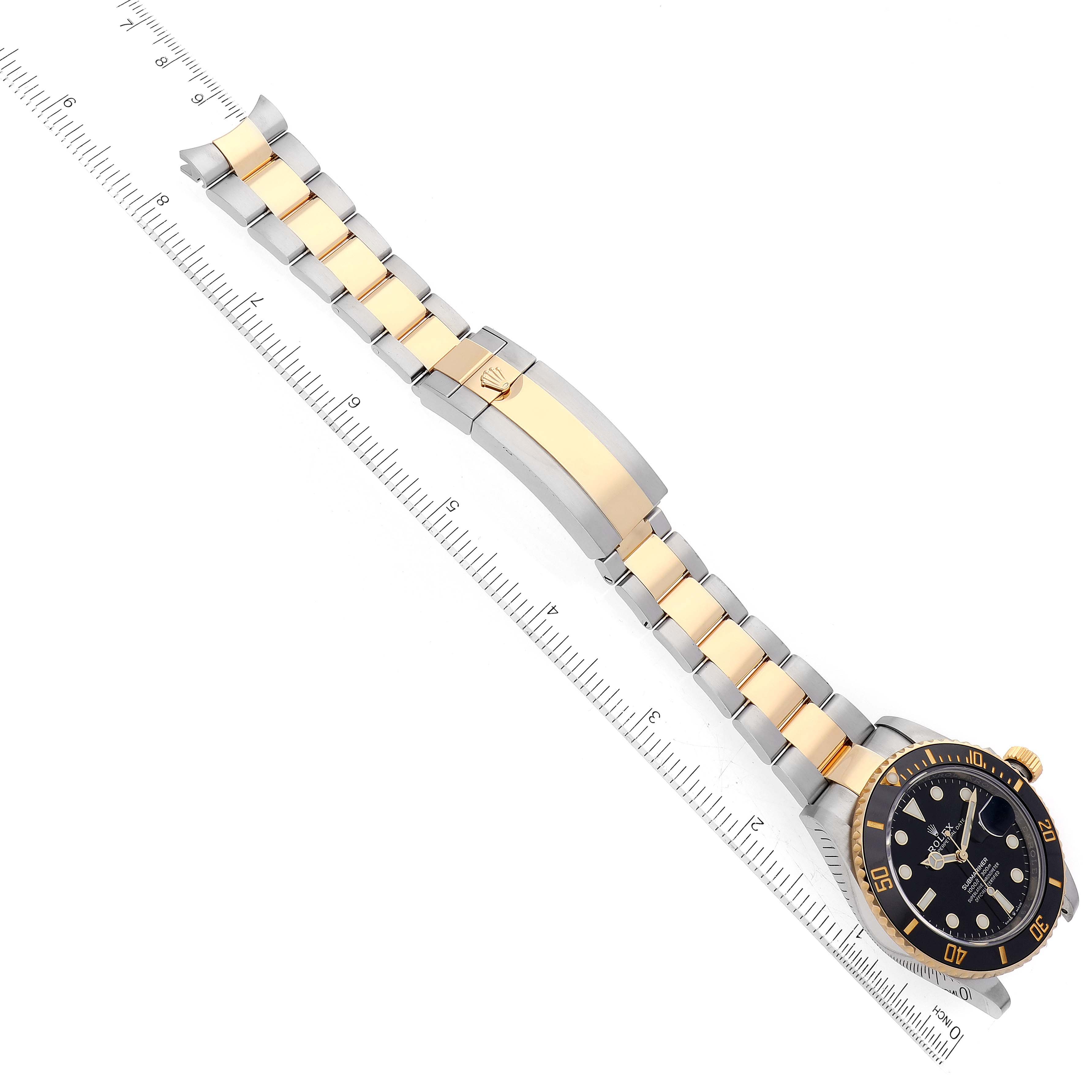 The image shows the Rolex Submariner 126613 Men
s Steel and Gold (two tone) Black Dial 126613 Men
s Steel and Gold (two tone) Black Dial watch from an overhead angle, highlighting its bracelet and face, placed alongside a ruler for scale.