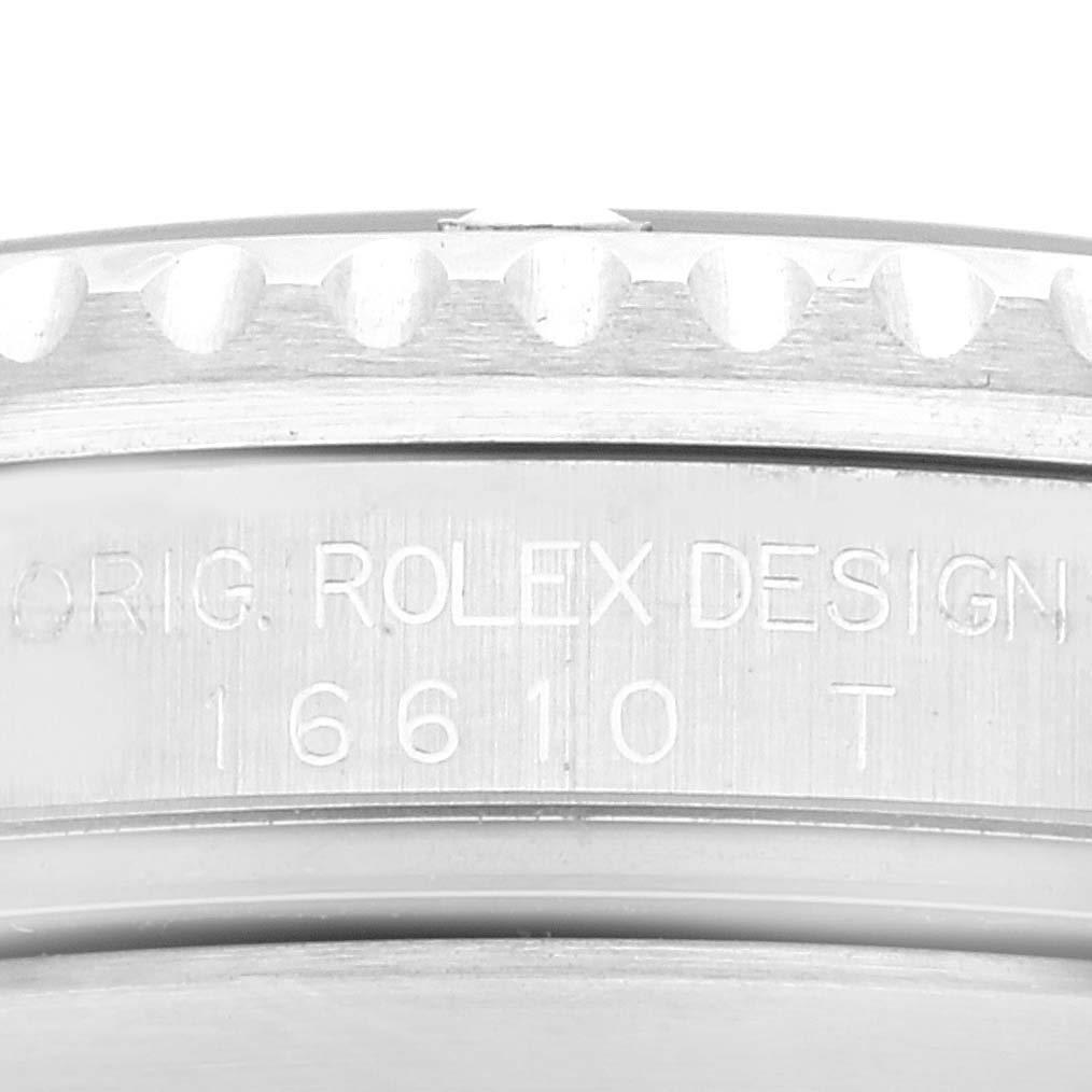The image shows a close-up of the side of a Rolex Submariner 16610 Men's Stainless Steel Black Dial 16610 Men's Stainless Steel Black Dial watch, focusing on the engraving "ORIG. ROLEX DESIGN 16610 T."