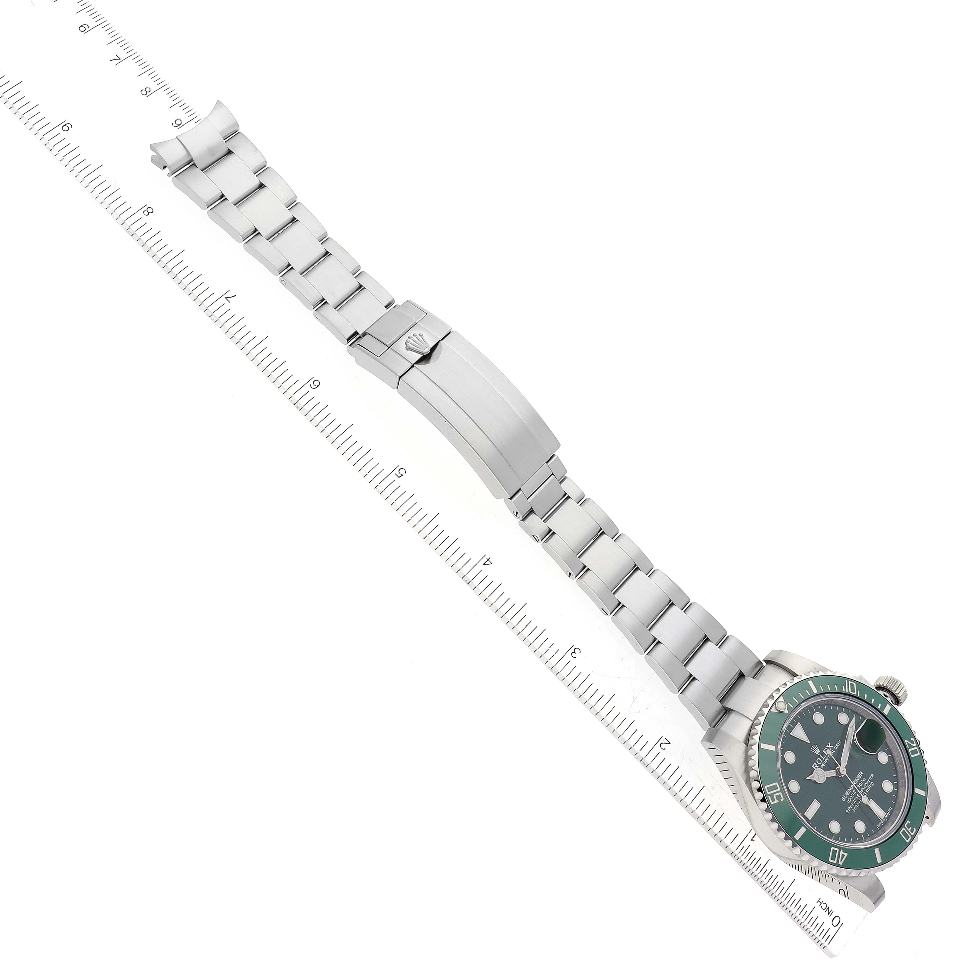 The image shows a top-down view of a Rolex Submariner 116610LV Men
s Stainless Steel Green Dial 116610LV Men
s Stainless Steel Green Dial watch, highlighting its dial, bracelet, and clasp alongside a ruler.
