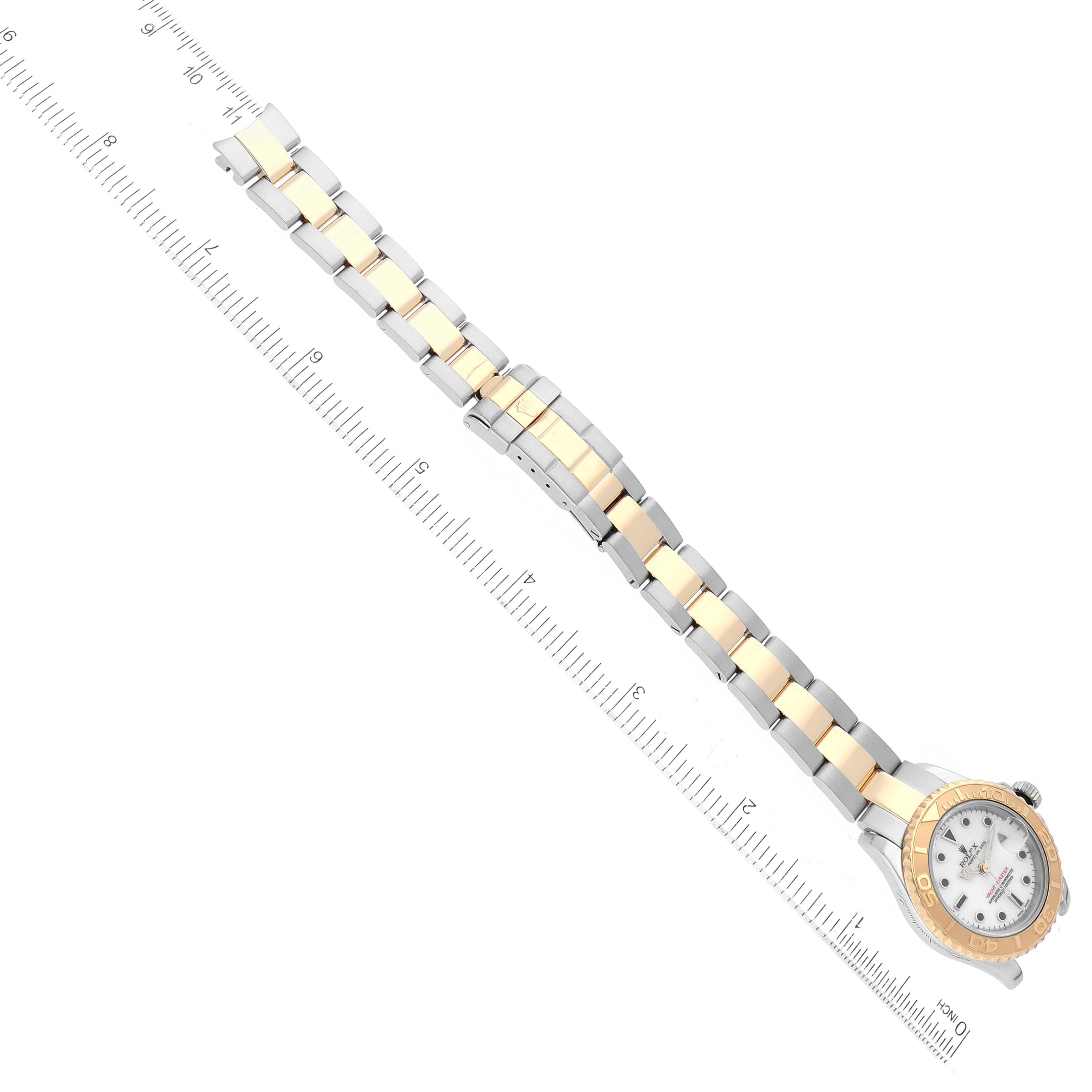 The Rolex Yacht-Master 169623 Women's Steel and Gold (two tone) White Dial 169623 Women's Steel and Gold (two tone) White Dial watch is shown from a top-down angle, displaying its bracelet and face alongside a ruler for scale.