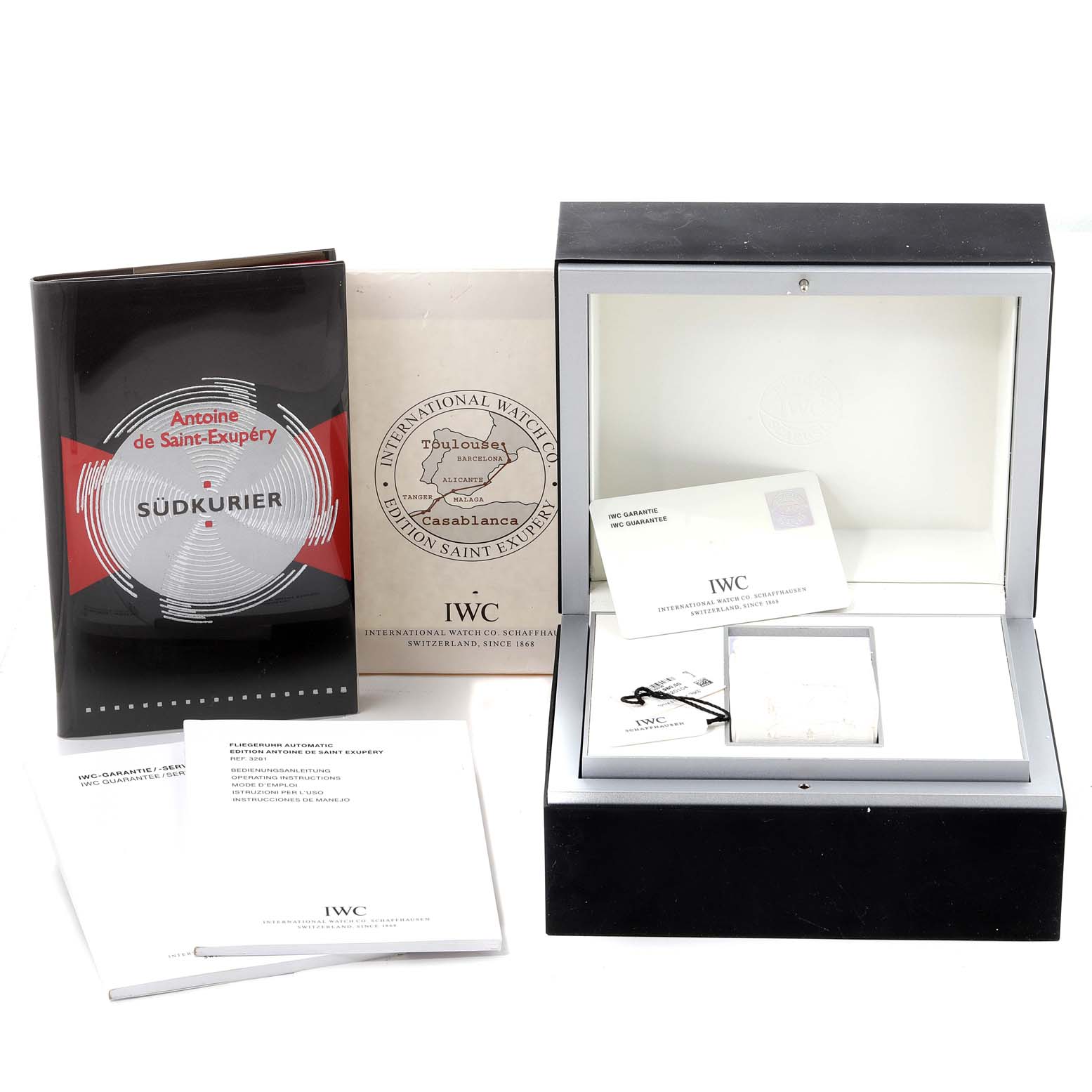 The image shows accessories for the IWC Pilot IW320104 Men's Stainless Steel Brown Dial IW320104 Men's Stainless Steel Brown Dial model, including a book, warranty card, and an open watch box.