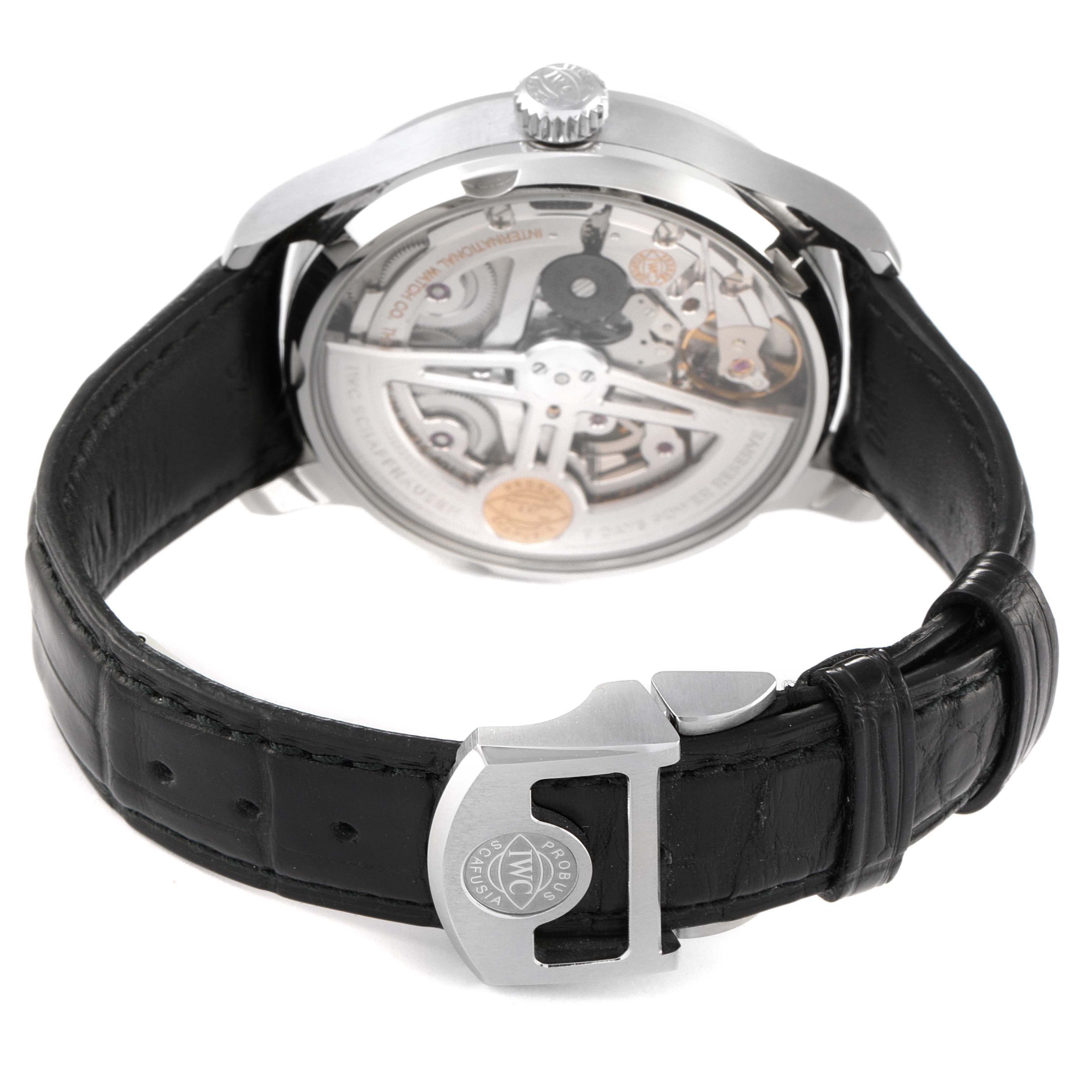 The image shows the back view and movement of an IWC Portuguese IW500704 Men's Stainless Steel Silver Dial IW500704 Men's Stainless Steel Silver Dial model watch, with a visible black leather strap and deployment clasp.