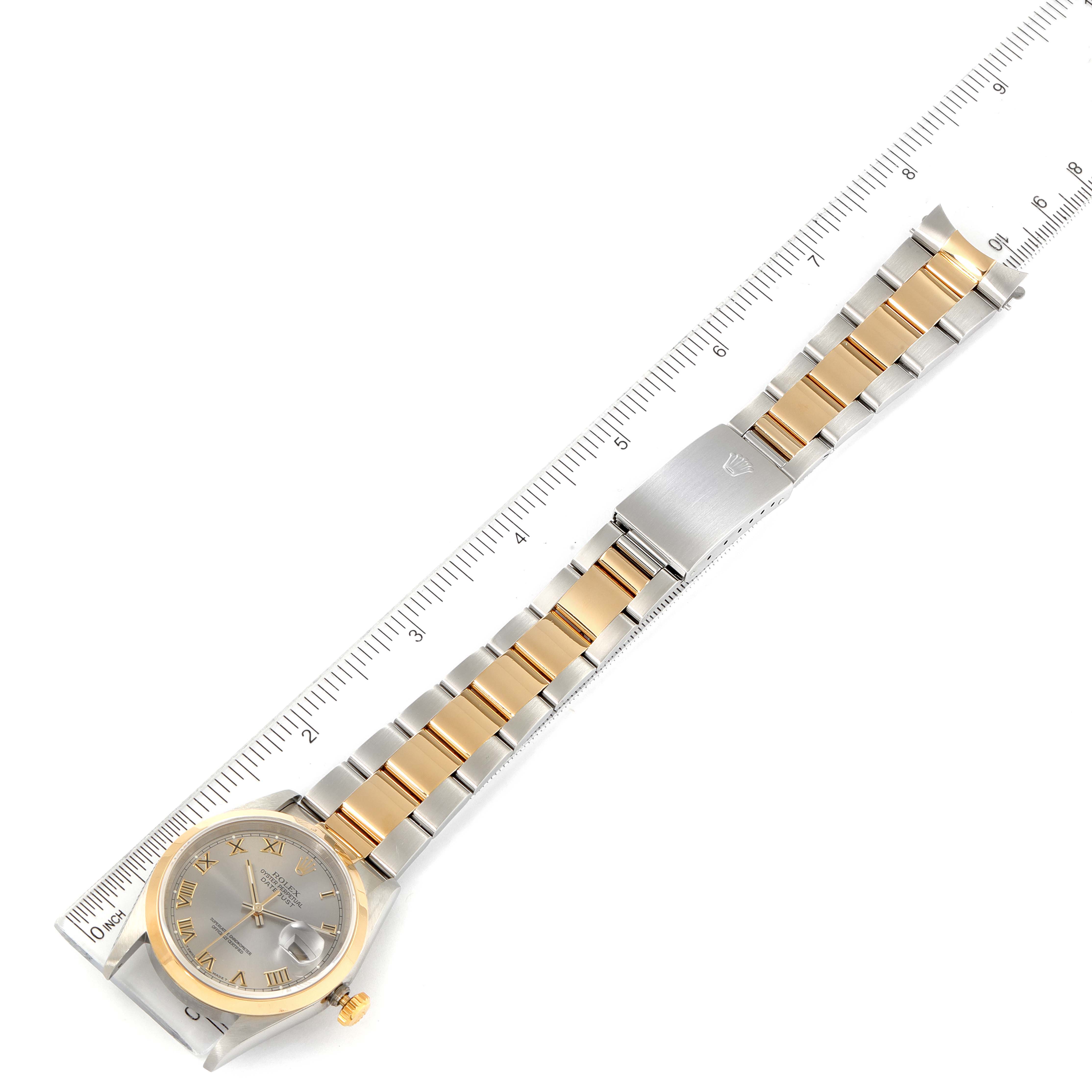 The image shows a top view of a Rolex Datejust 16203 Men
s Steel and Gold (two tone) Grey Dial 16203 Men
s Steel and Gold (two tone) Grey Dial watch, featuring the watch face, bracelet, and clasp beside a ruler for scale.