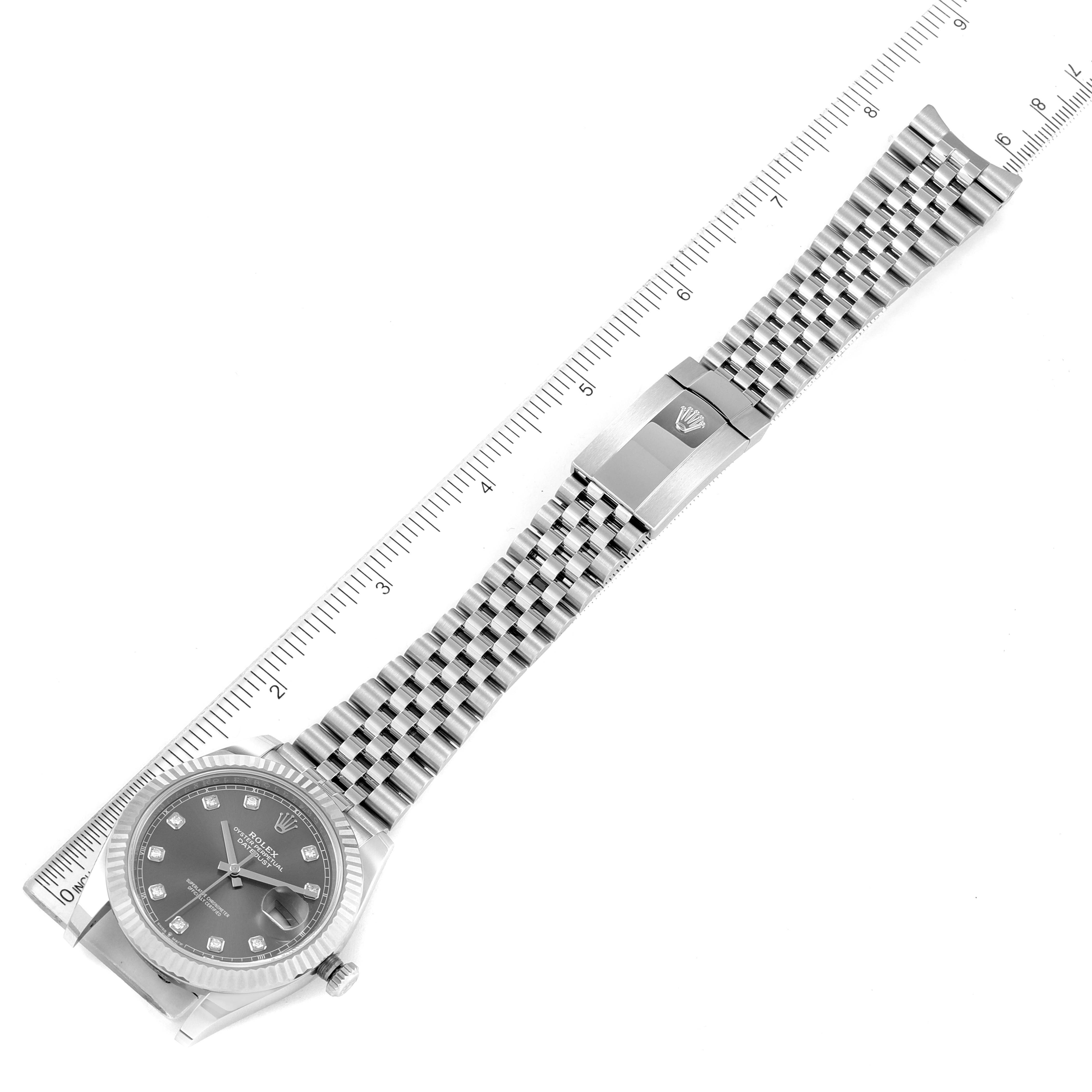 The image shows a Rolex Datejust 41 126334 Men
s Stainless Steel Grey Dial 126334 Men
s Stainless Steel Grey Dial watch laid flat, displaying the face, bracelet, and clasp alongside a ruler for scale.