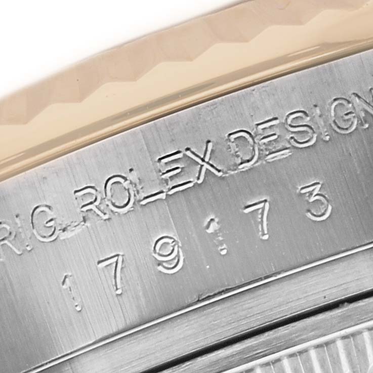The image shows an engraved serial number and "ROLEX DESIGN" on the side of a Rolex Datejust 179173 Women's Steel and Gold (two tone) Black Dial 179173 Women's Steel and Gold (two tone) Black Dial watch case.