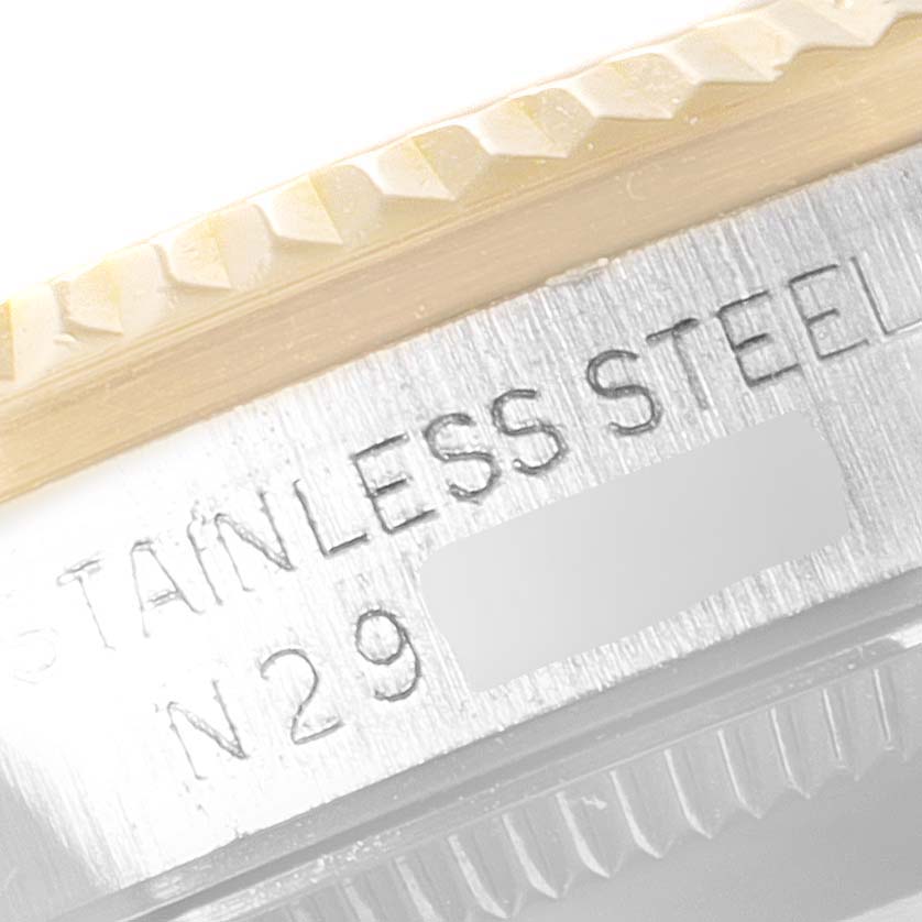 This close-up shot of the Mid-Size Rolex watch shows part of the bezel and the engraving "STAINLESS STEEL" with a partial serial number.