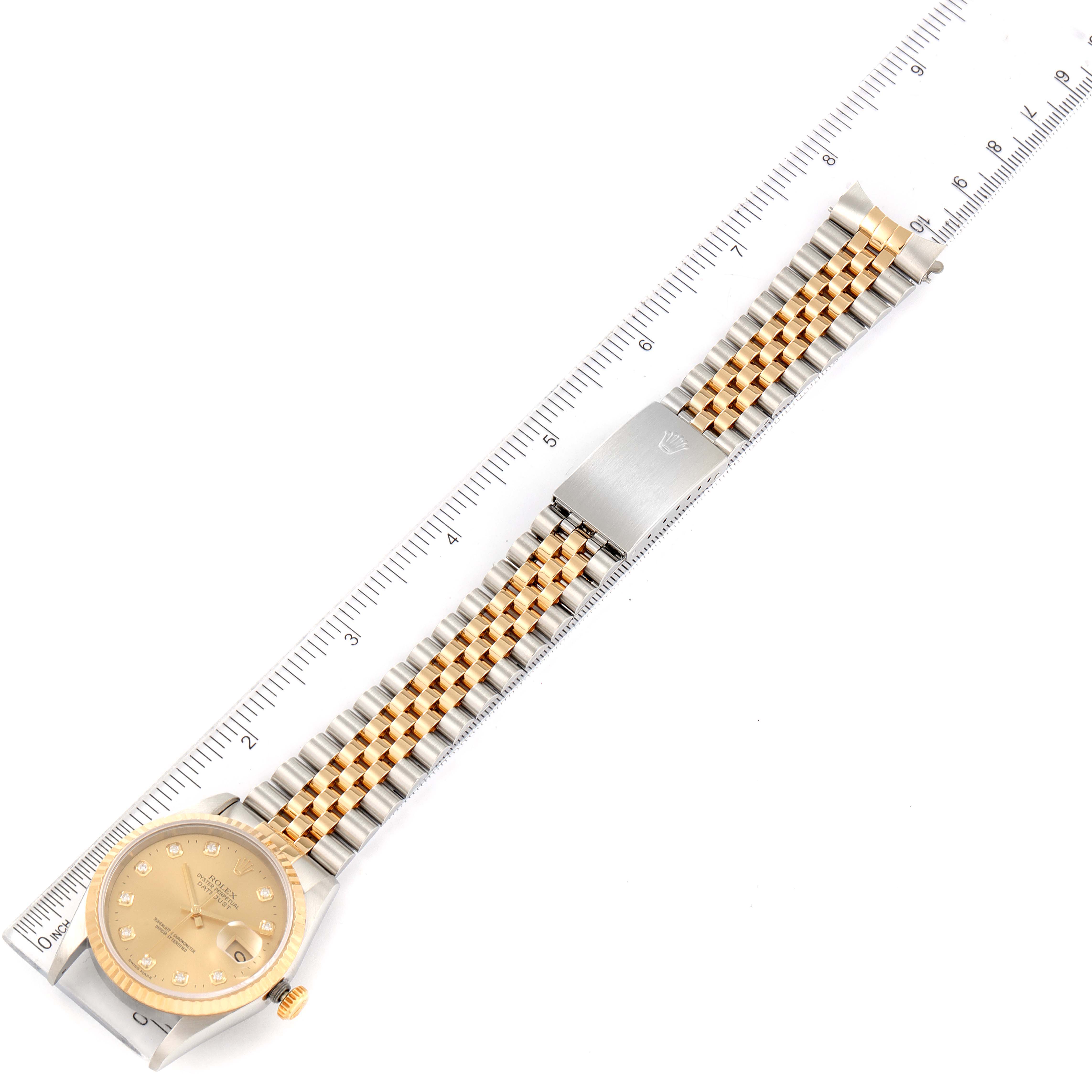 The Rolex Datejust 16233 Men
s Steel and Gold (two tone) Champagne Dial 16233 Men
s Steel and Gold (two tone) Champagne Dial watch is shown from an overhead angle, displaying its dial, bracelet, and clasp, alongside a ruler for scale.