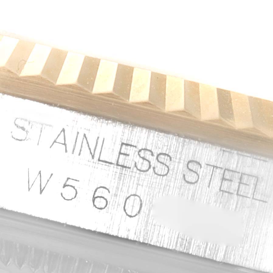 The image shows a close-up of the fluted bezel and stainless steel case of a Rolex Datejust 16233 Men
s Steel and Gold (two tone) Champagne Dial 16233 Men
s Steel and Gold (two tone) Champagne Dial watch, including part of the model
s engraving.