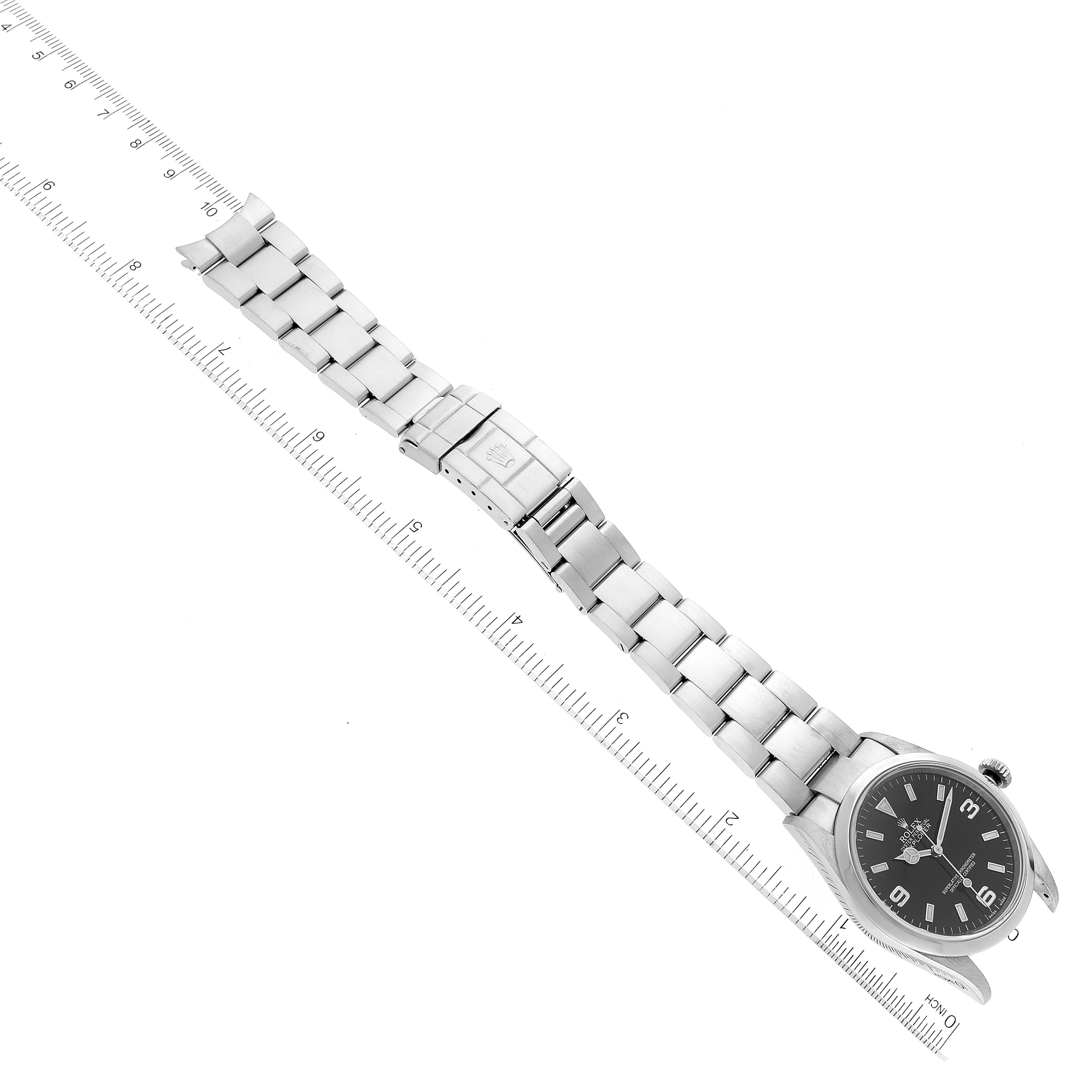 The image shows a Rolex Explorer 114270 Men's Stainless Steel Black Dial 114270 Men's Stainless Steel Black Dial watch at an overhead angle, highlighting the face, bracelet, and clasp alongside a measuring ruler.