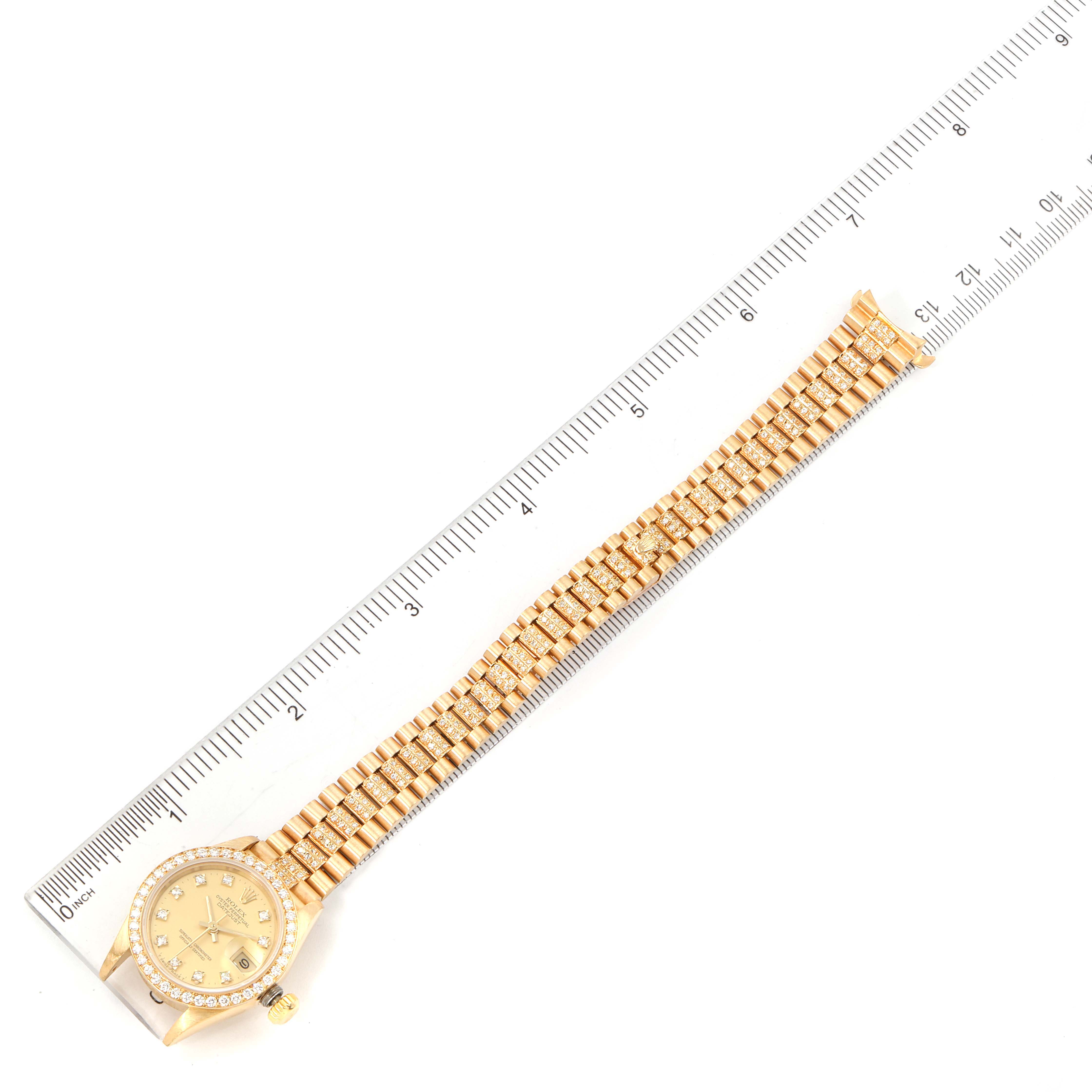The image shows a top-down view of a Rolex President 69138 Women's Yellow Gold Champagne Dial 69138 Women's Yellow Gold Champagne Dial model watch alongside a ruler for scale.