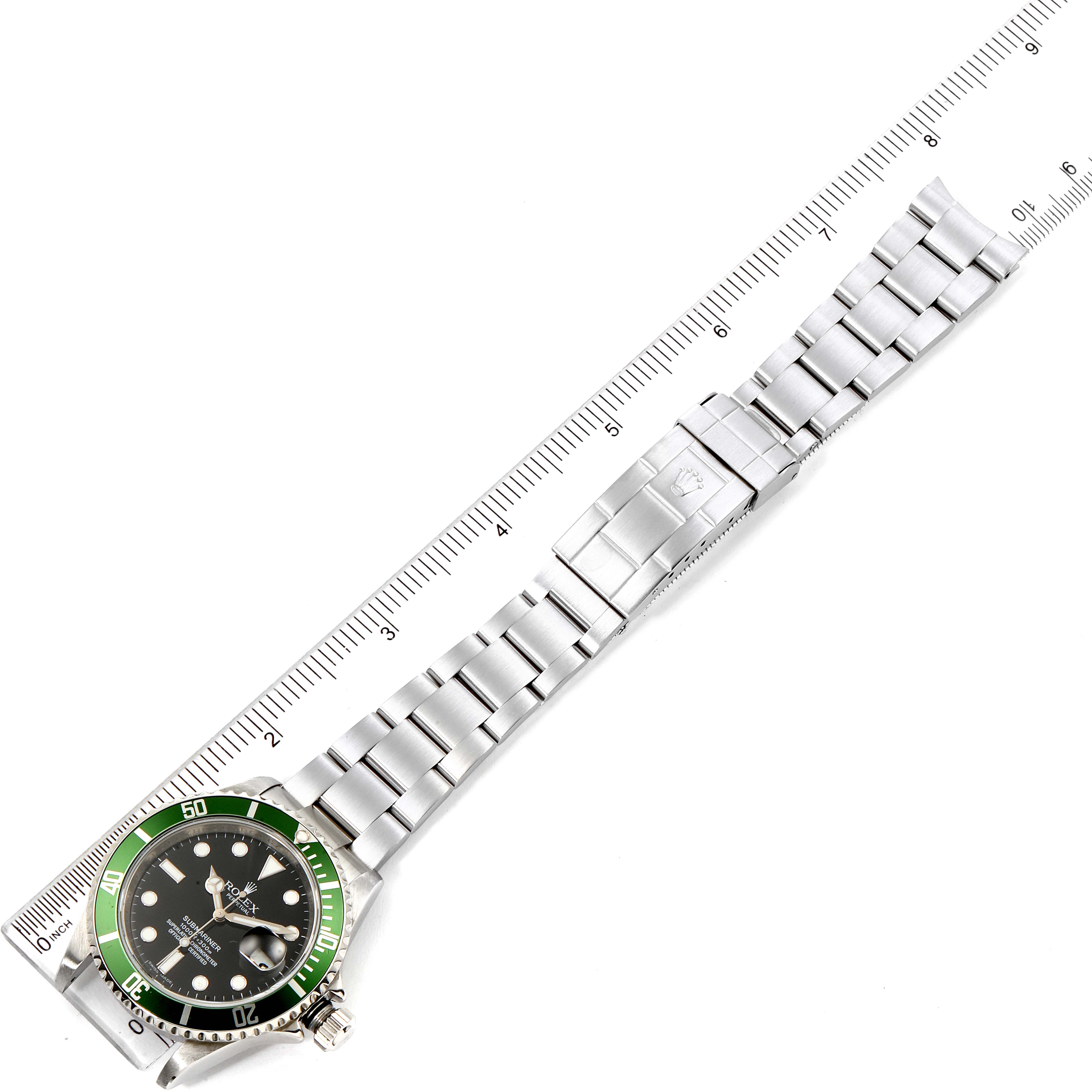 This image shows the Rolex Submariner 16610LV Men's Stainless Steel Black Dial 16610LV Men's Stainless Steel Black Dial watch with a green bezel, black dial, and silver bracelet, laid flat next to a ruler.