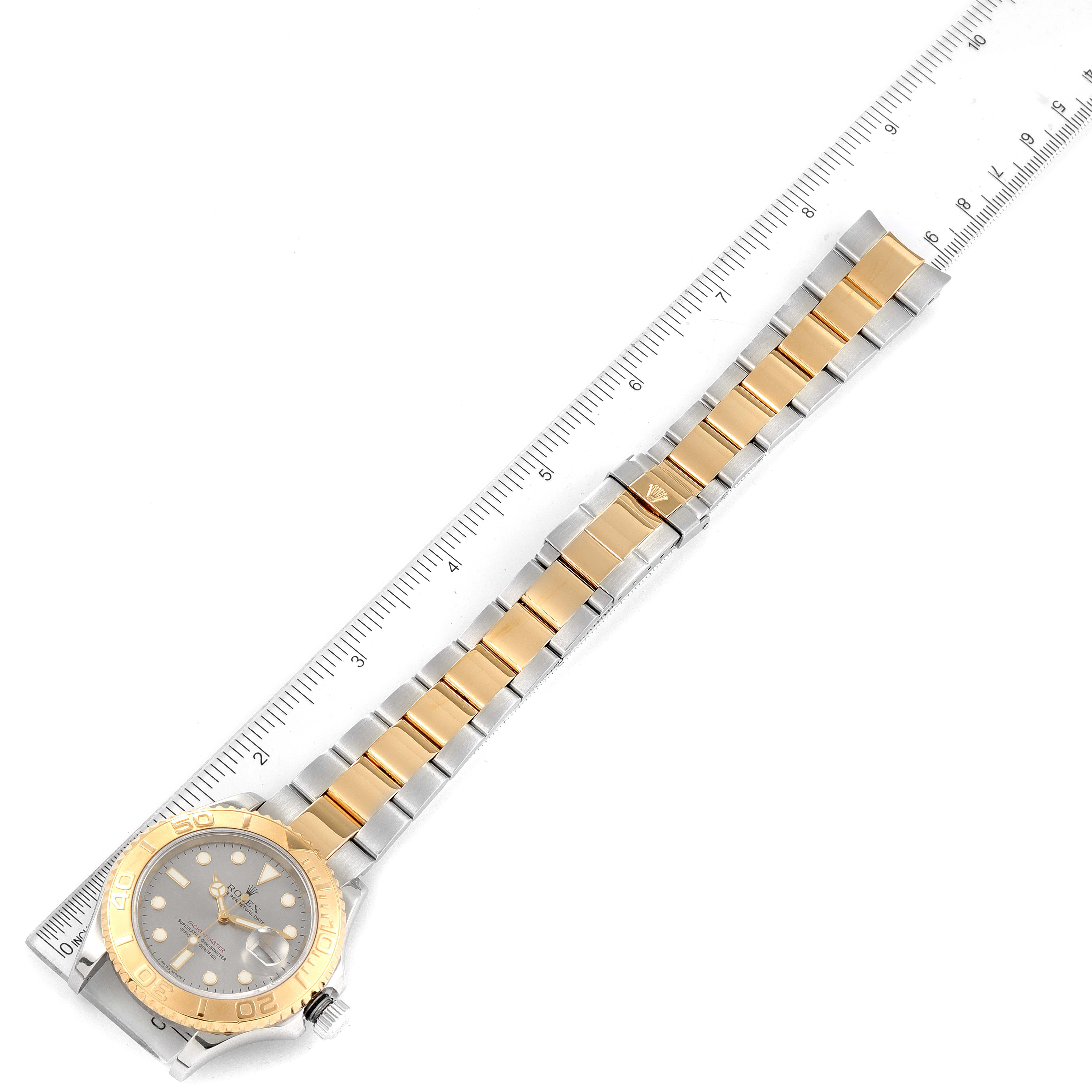 The Rolex Yacht-Master 16623 Men's Steel and Gold (two tone) Grey Dial 16623 Men's Steel and Gold (two tone) Grey Dial watch is shown from a top-down angle, displaying the entire bracelet and face next to a ruler for scale.