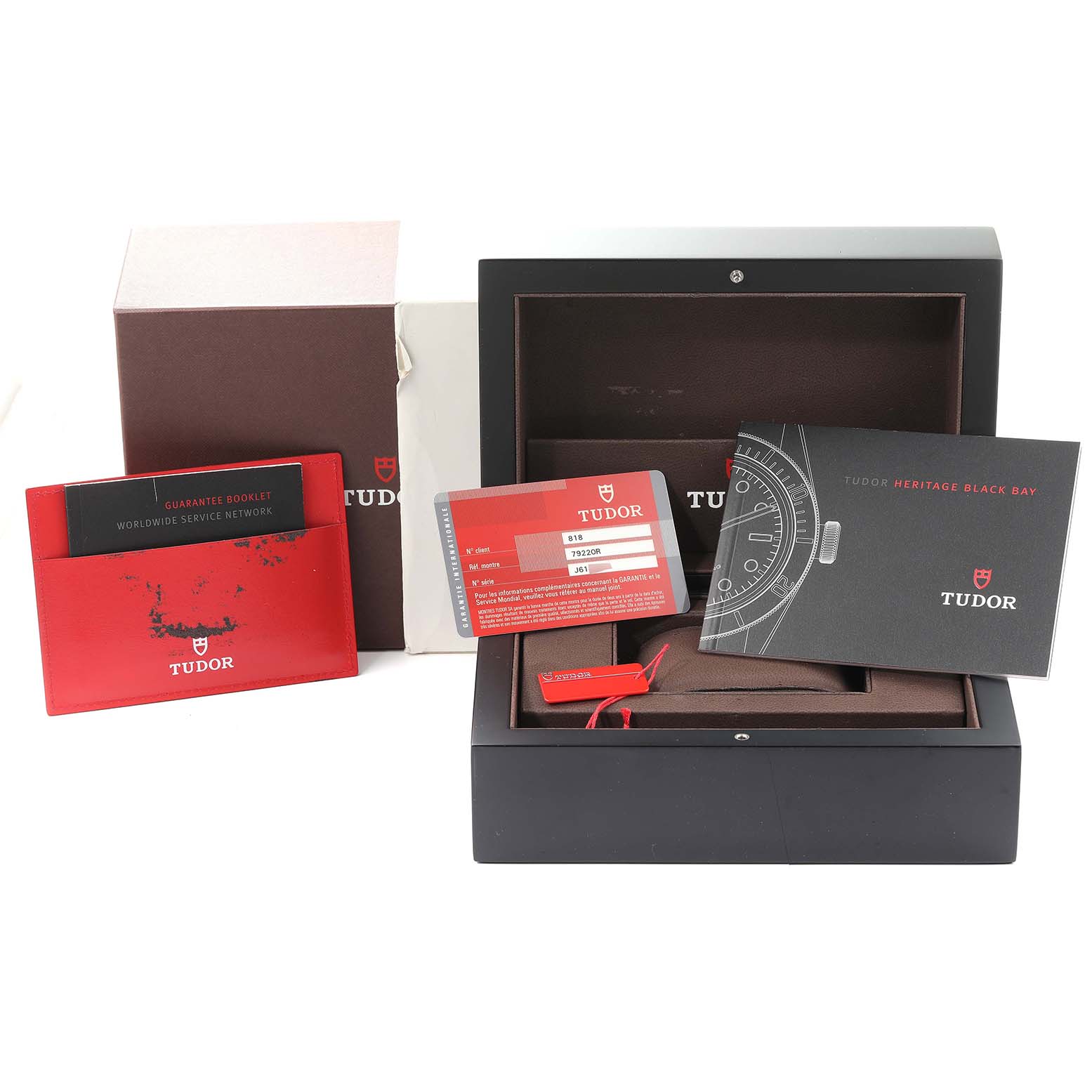 The image shows packaging, booklets, and warranty card for a Tudor Heritage Black Bay 79220R Men's Stainless Steel Black Dial 79220R Men's Stainless Steel Black Dial watch at a front angle.