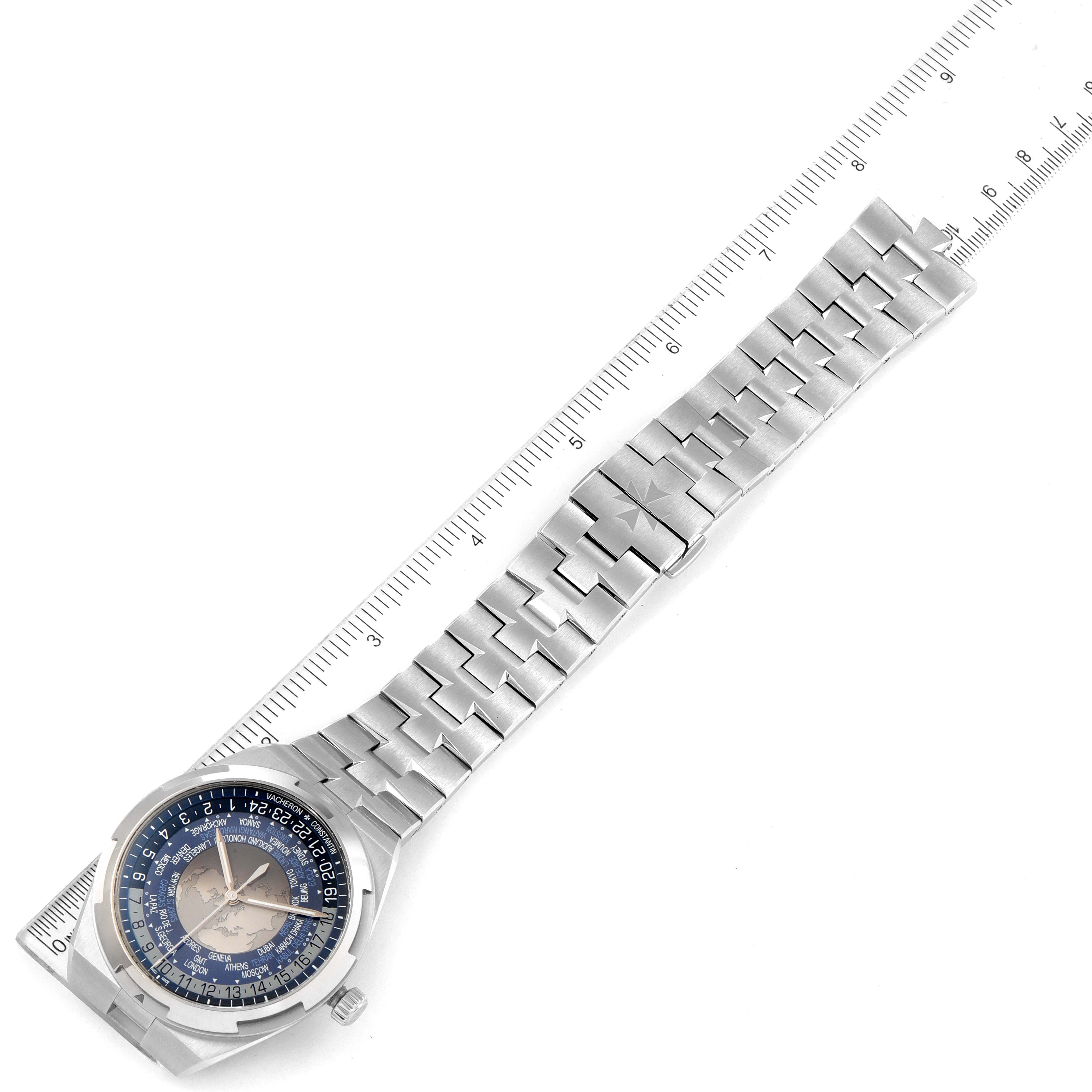 This image shows the Vacheron Constantin Overseas 7700V/110A-B172 Men
s Stainless Steel Blue Dial 7700V/110A-B172 Men
s Stainless Steel Blue Dial watch laid flat with its silver bracelet and blue dial, accompanied by a ruler for scale.