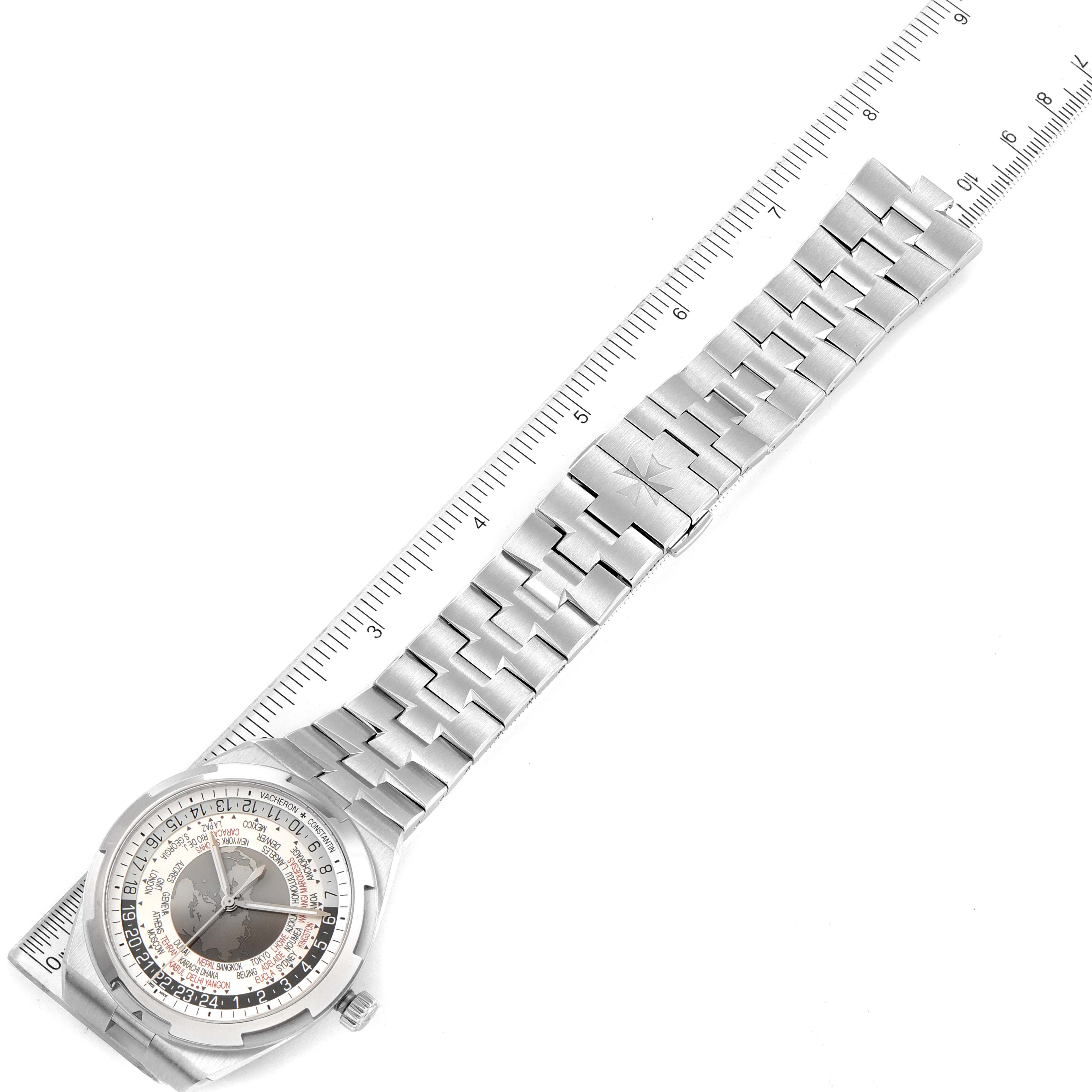 The image shows an overhead view of the Vacheron Constantin Overseas 7700V/110A-B129 Men's Stainless Steel Silver Dial 7700V/110A-B129 Men's Stainless Steel Silver Dial watch, featuring its full dial and bracelet laid out flat adjacent to a ruler.
