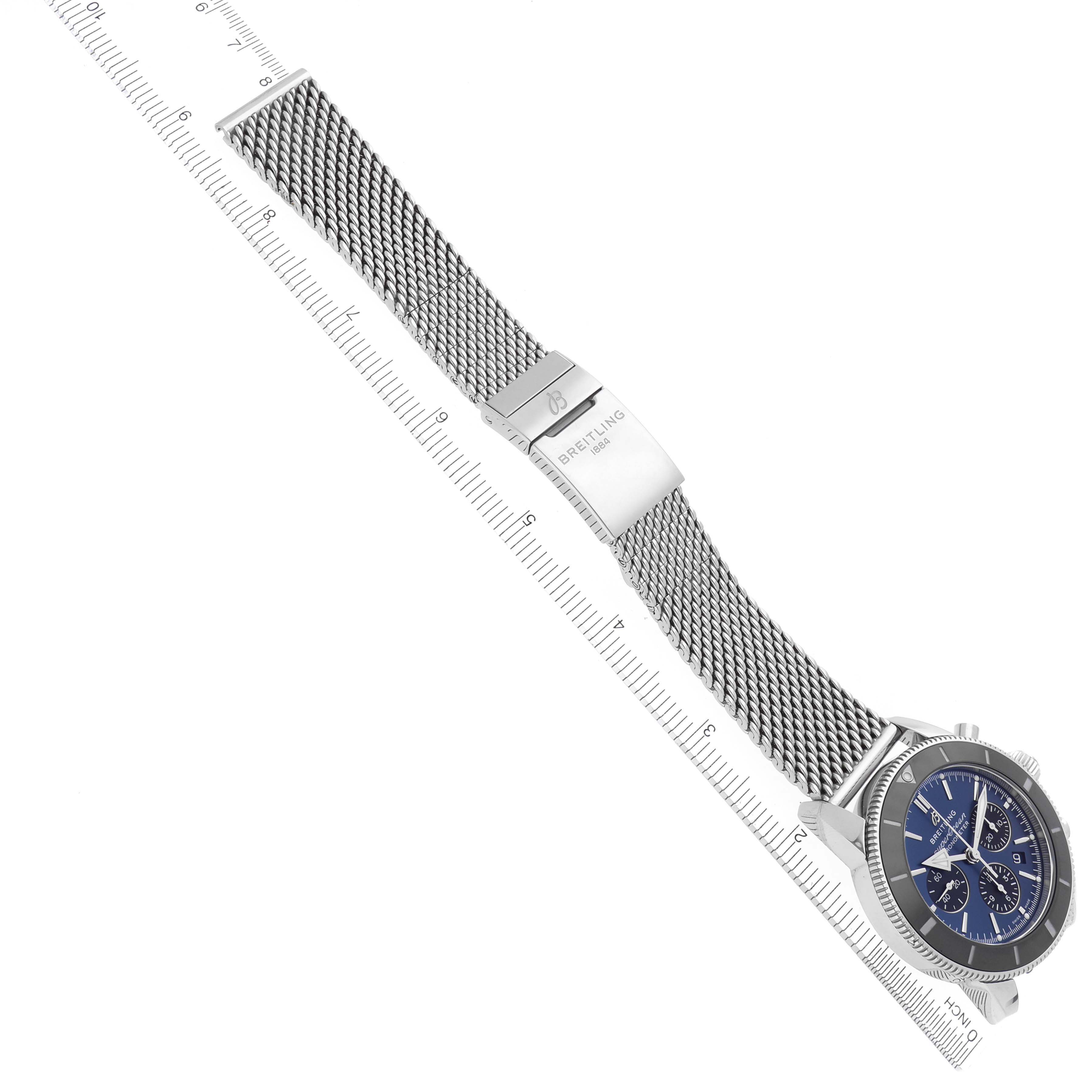 The Breitling Superocean AB0162121C1S1 Men's Stainless Steel Blue Dial AB0162121C1S1 Men's Stainless Steel Blue Dial watch is shown at an angle showcasing the mesh strap, clasp, and face with a ruler for scale.
