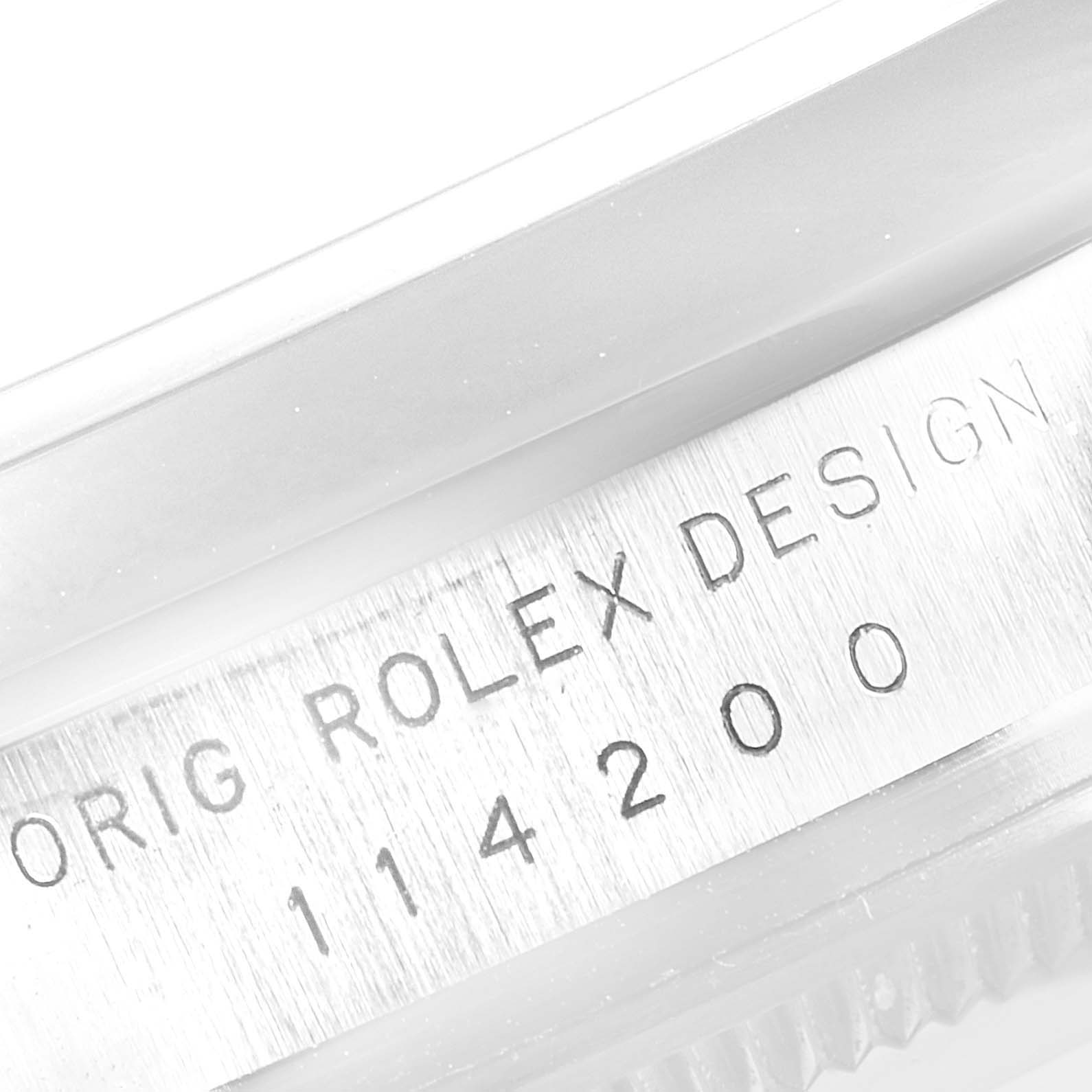 The image shows a close-up of the case side engraving of a Rolex Air-King 114200 Men's Stainless Steel Blue Dial 114200 Men's Stainless Steel Blue Dial watch, displaying the model number and "Rolex Design" engravings.