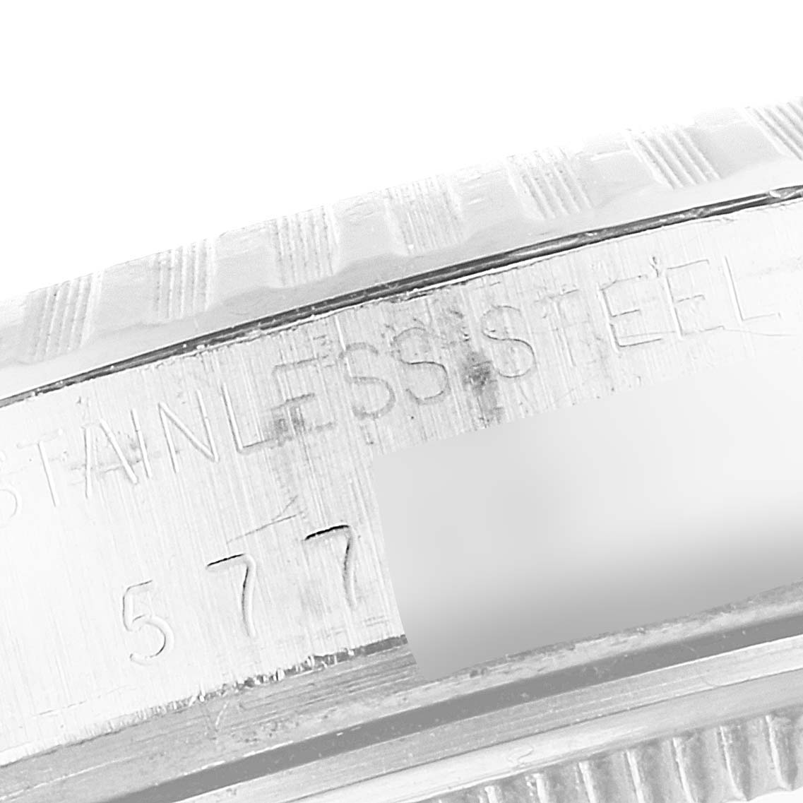 The image shows a close-up of the engraved bezel and case side of a Vintage Collection model by Rolex, highlighting the stainless steel material.