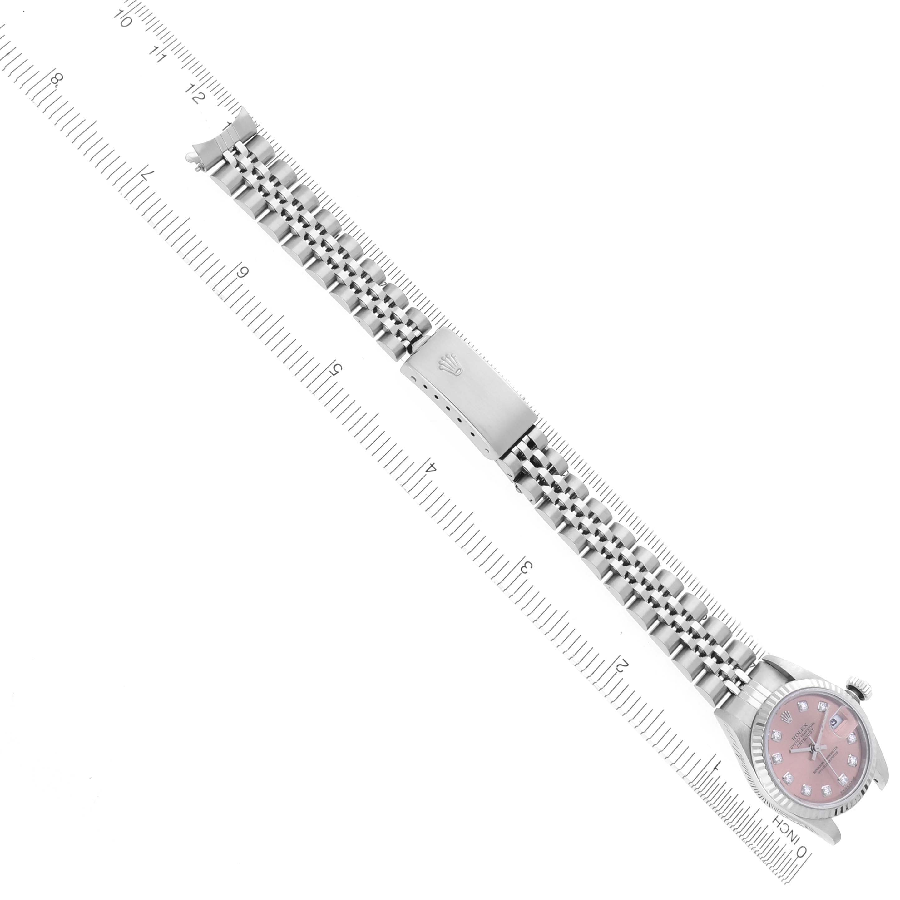 The Rolex Datejust 79174 Women's Stainless Steel Pink Dial 79174 Women's Stainless Steel Pink Dial watch is shown from an overhead view, displaying the face, bracelet, and clasp alongside a ruler.